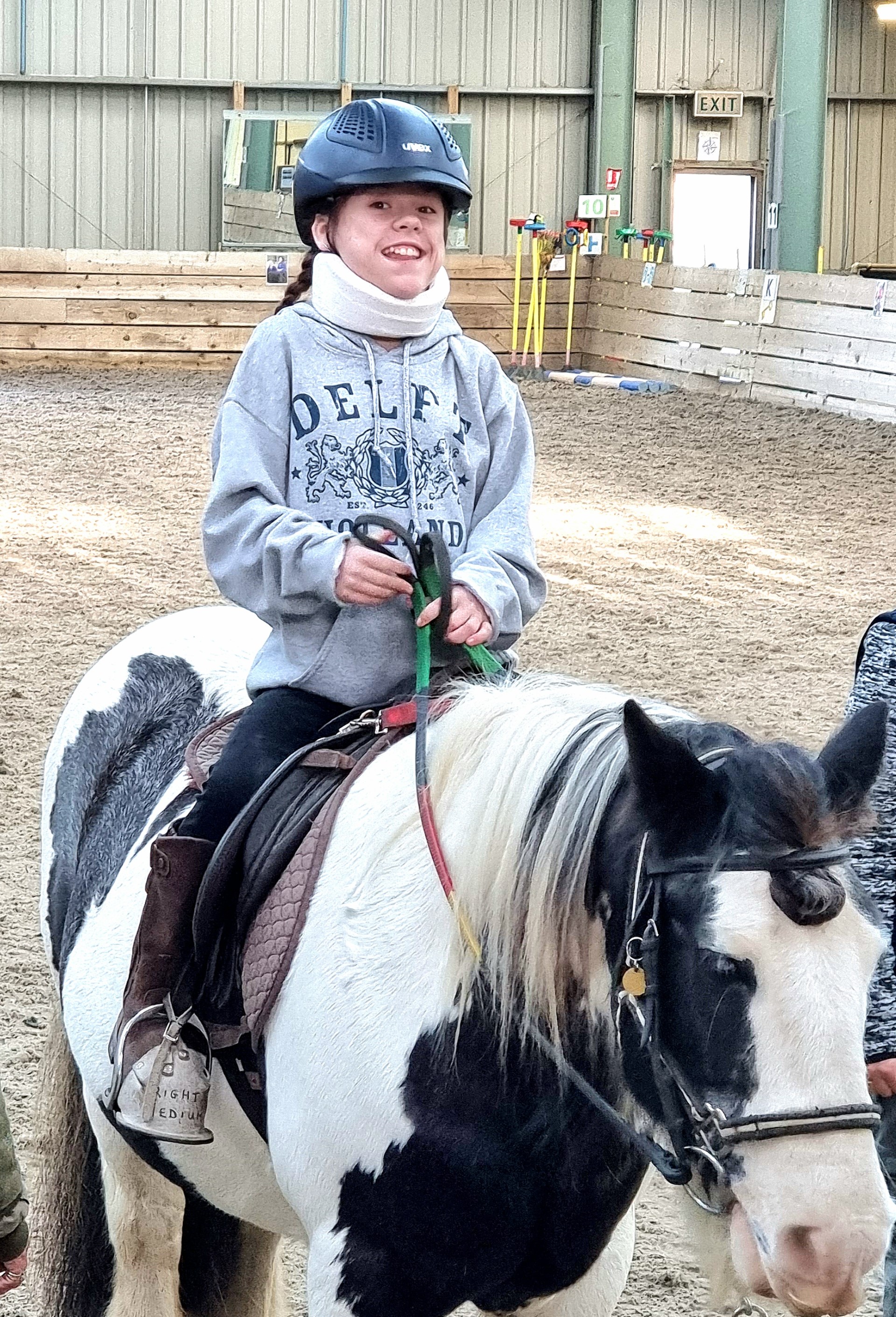 Carmela Chillery-Watson sitting on a horse wearing a grey jumper and smiling at the camera 