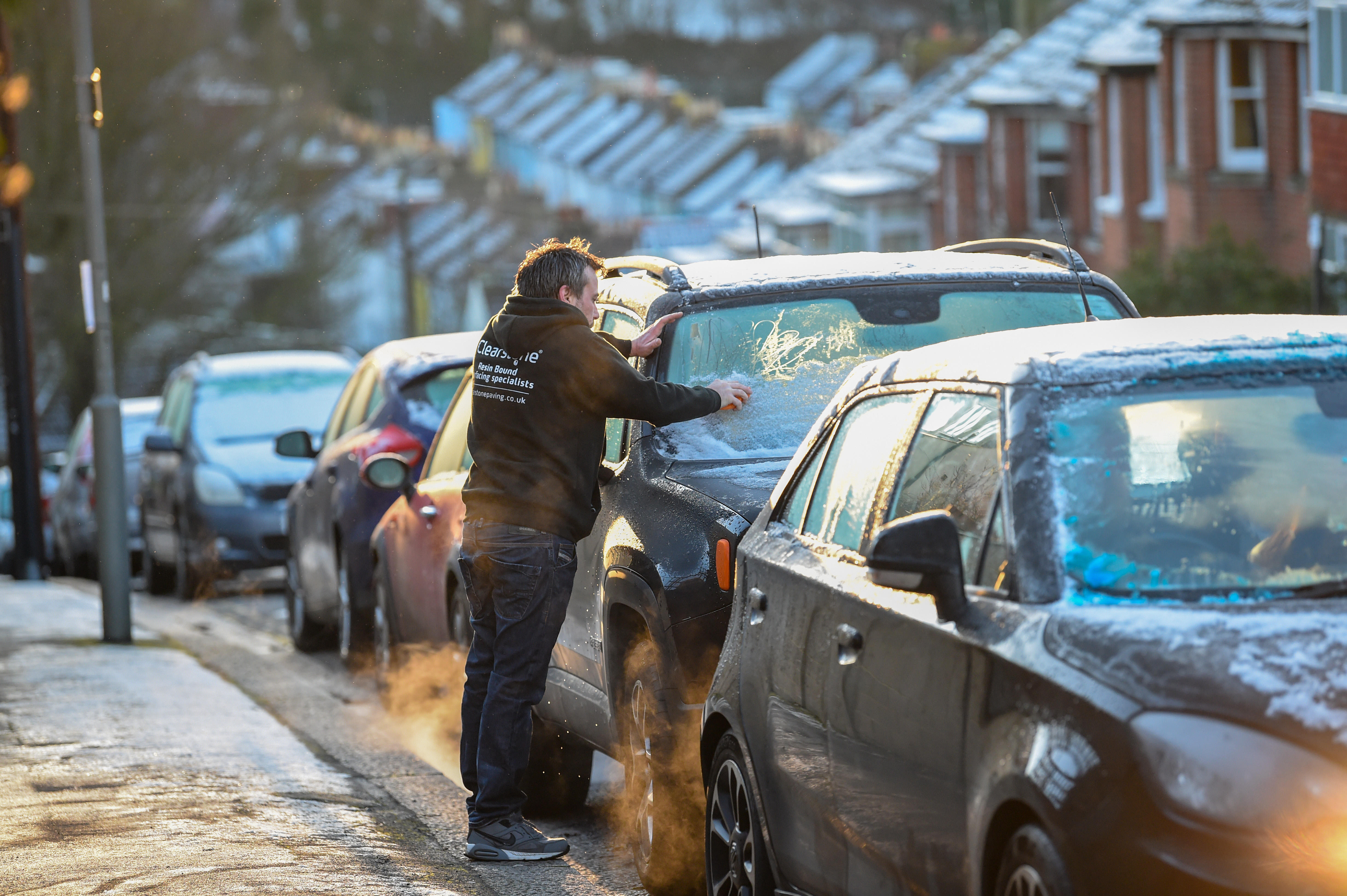 A motorist clearing ice off their windscreen