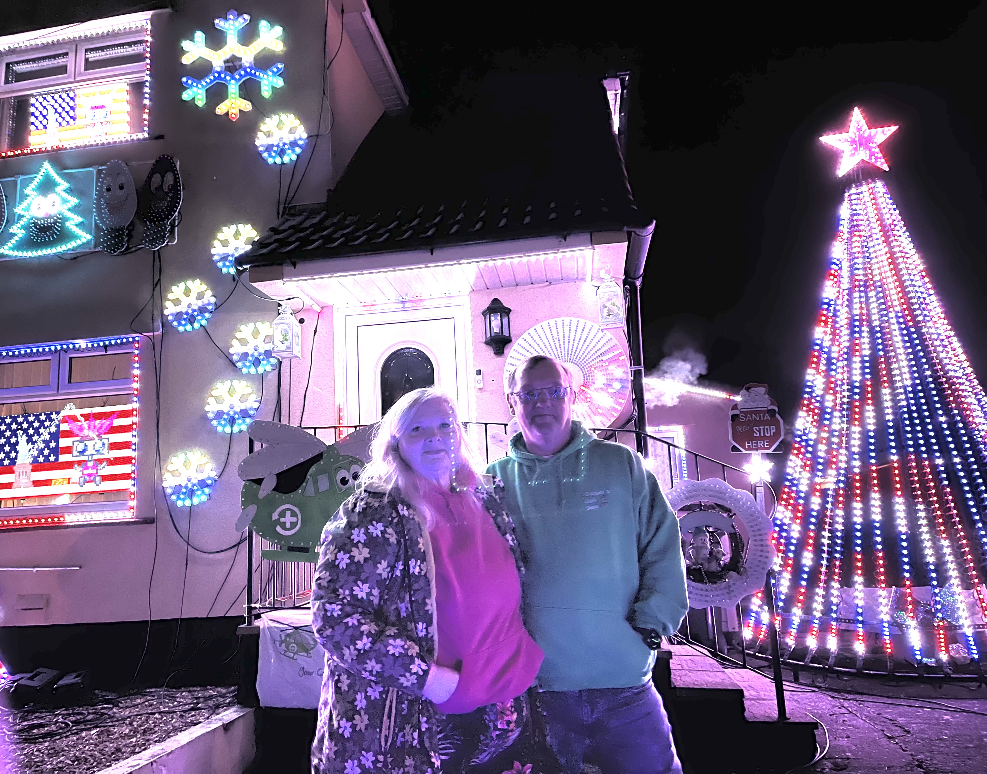 Ian and Ann Cooper standing together in front of their Christmas display 
