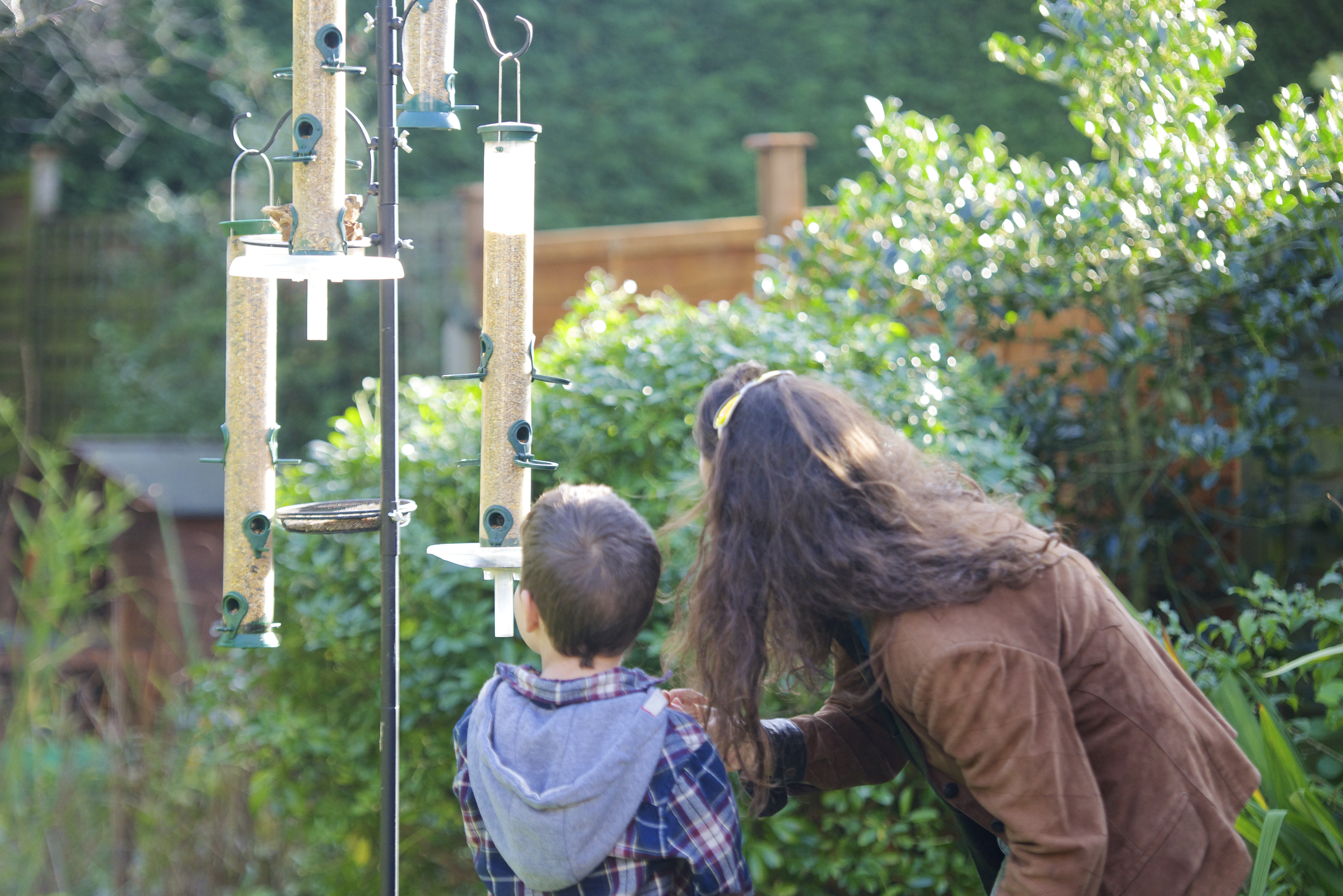 A mother helps her son put up a bird feeder (Rahul Thanki/rspb-images.com/PA)