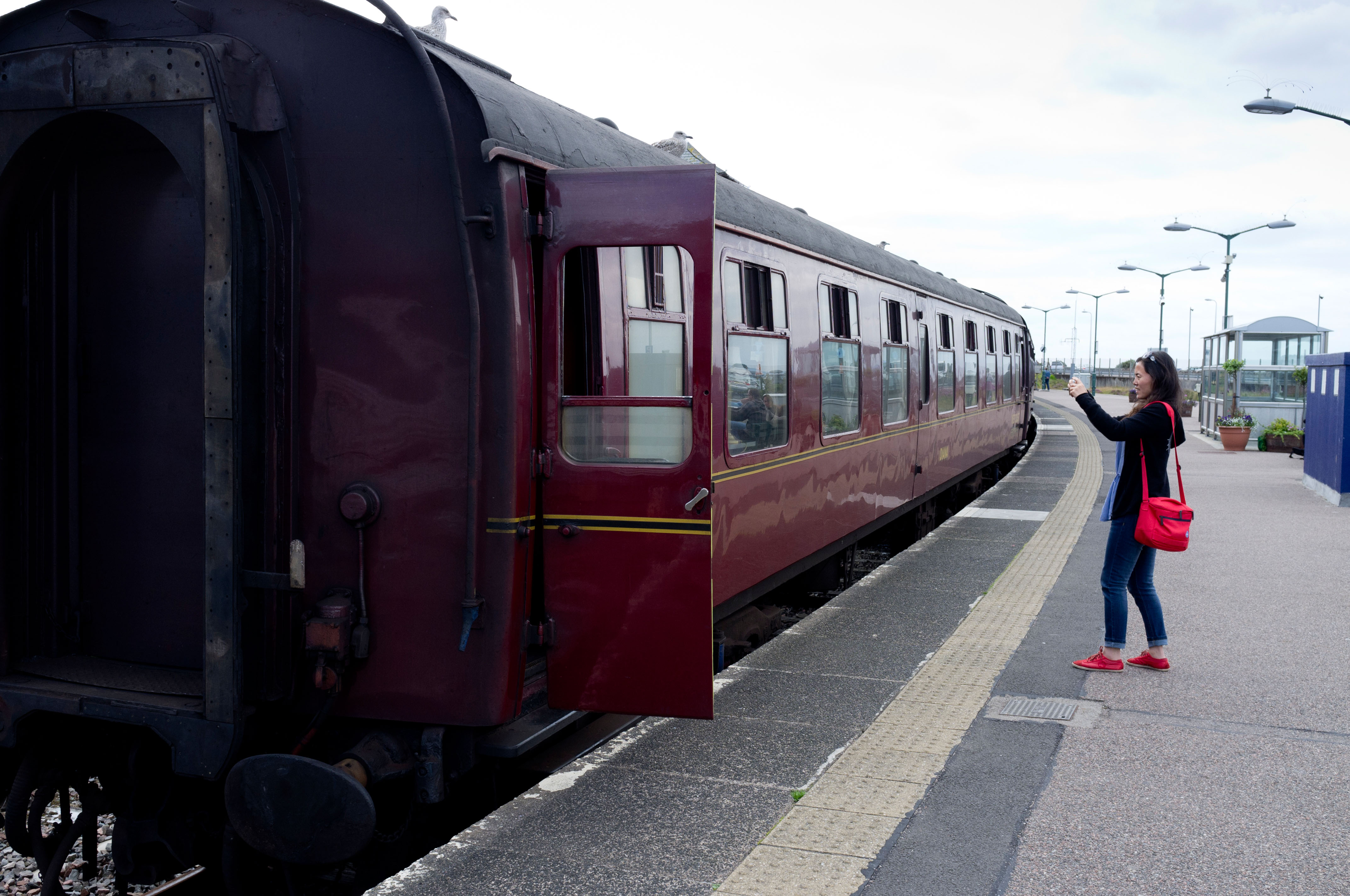 A Tourist taking a picture of the Jacobite steam train at Mallaig train station Scotland UK