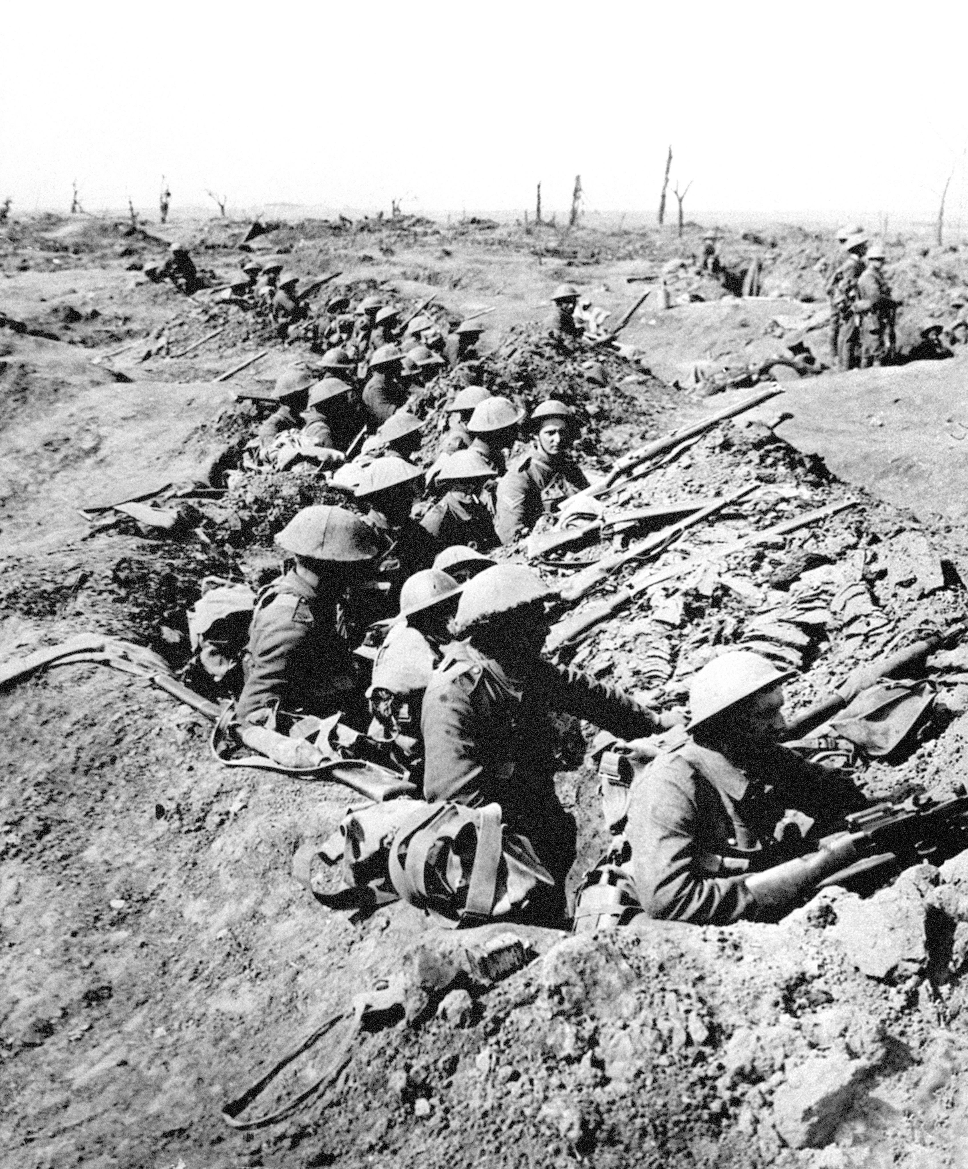 British infantrymen occupy a shallow trench in a ruined landscape before an advance during the Battle of the Somme 