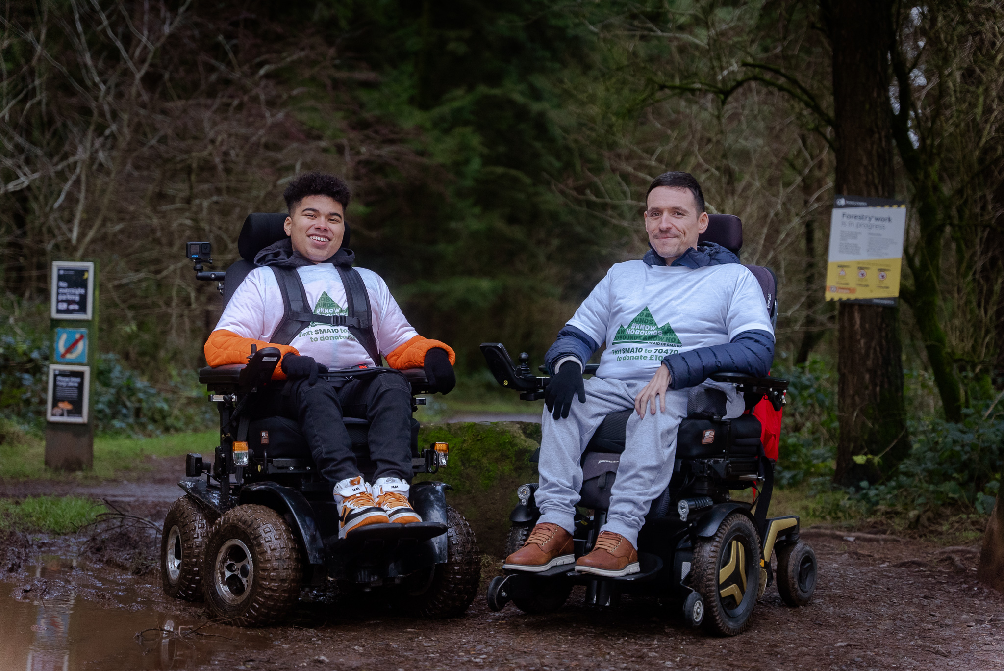 Two men in powered wheelchairs on a muddy track