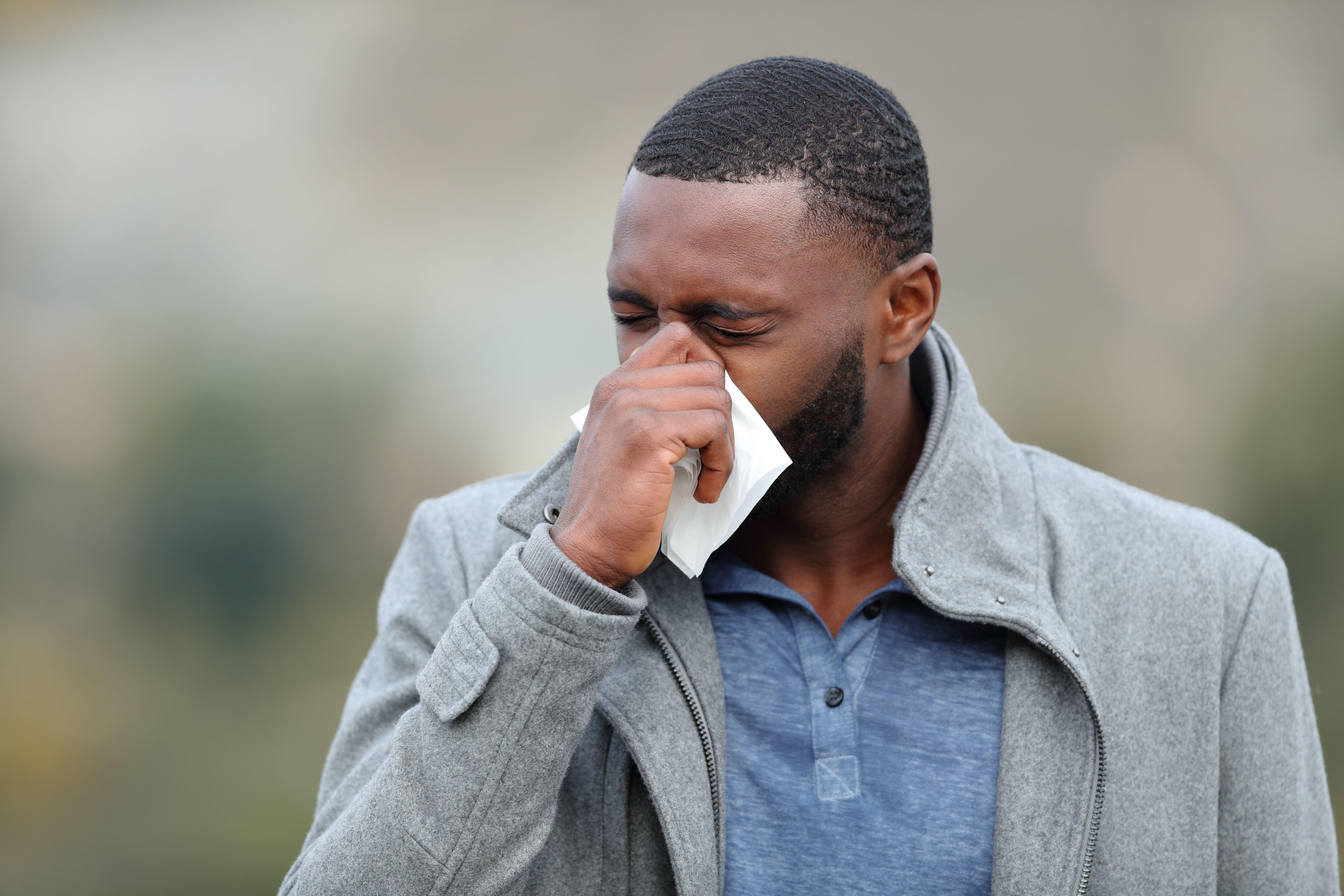 A man with a cold blowing his nose