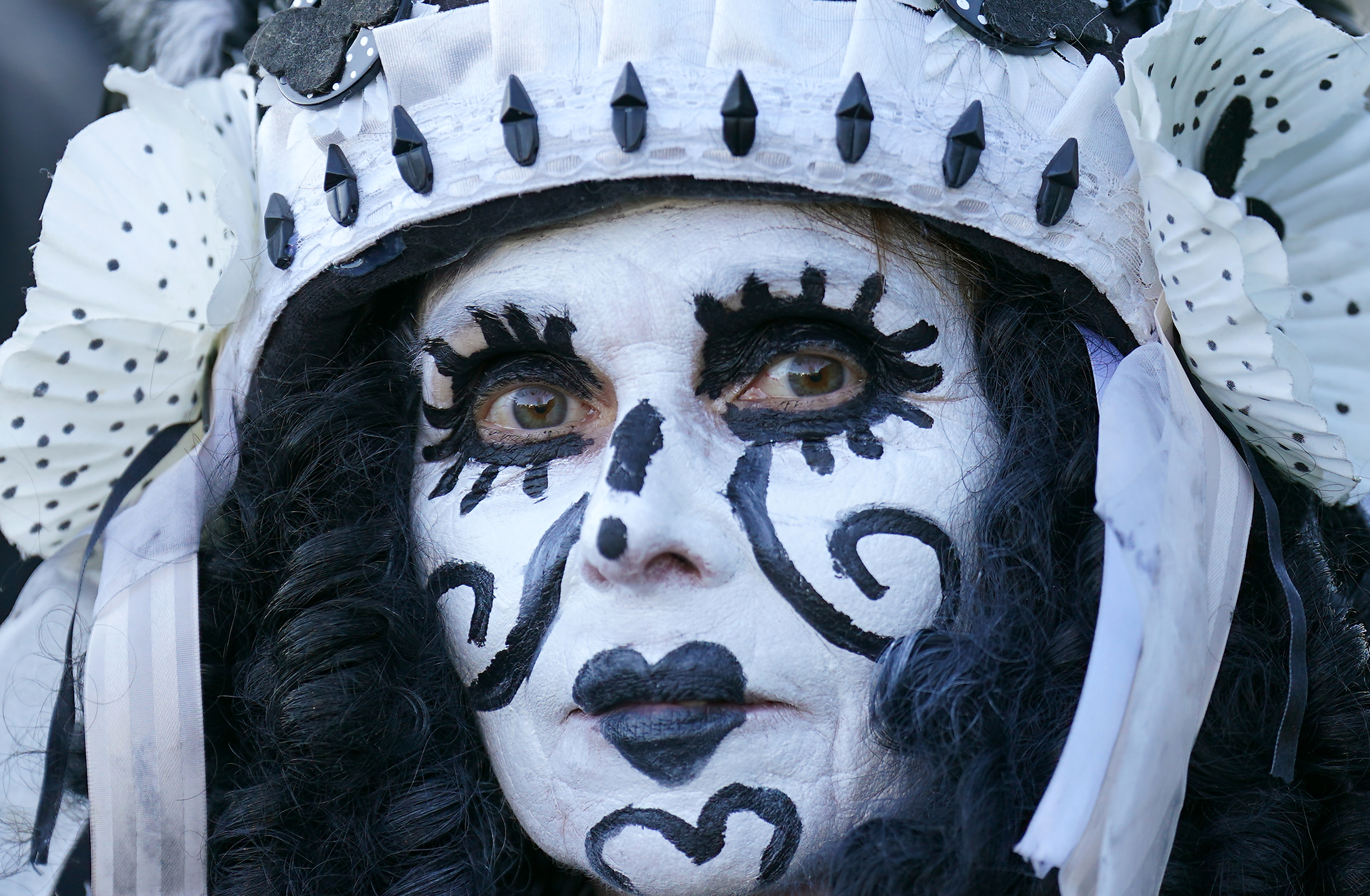 A close up of a woman wearing dramatic black and white face paint during the festival 