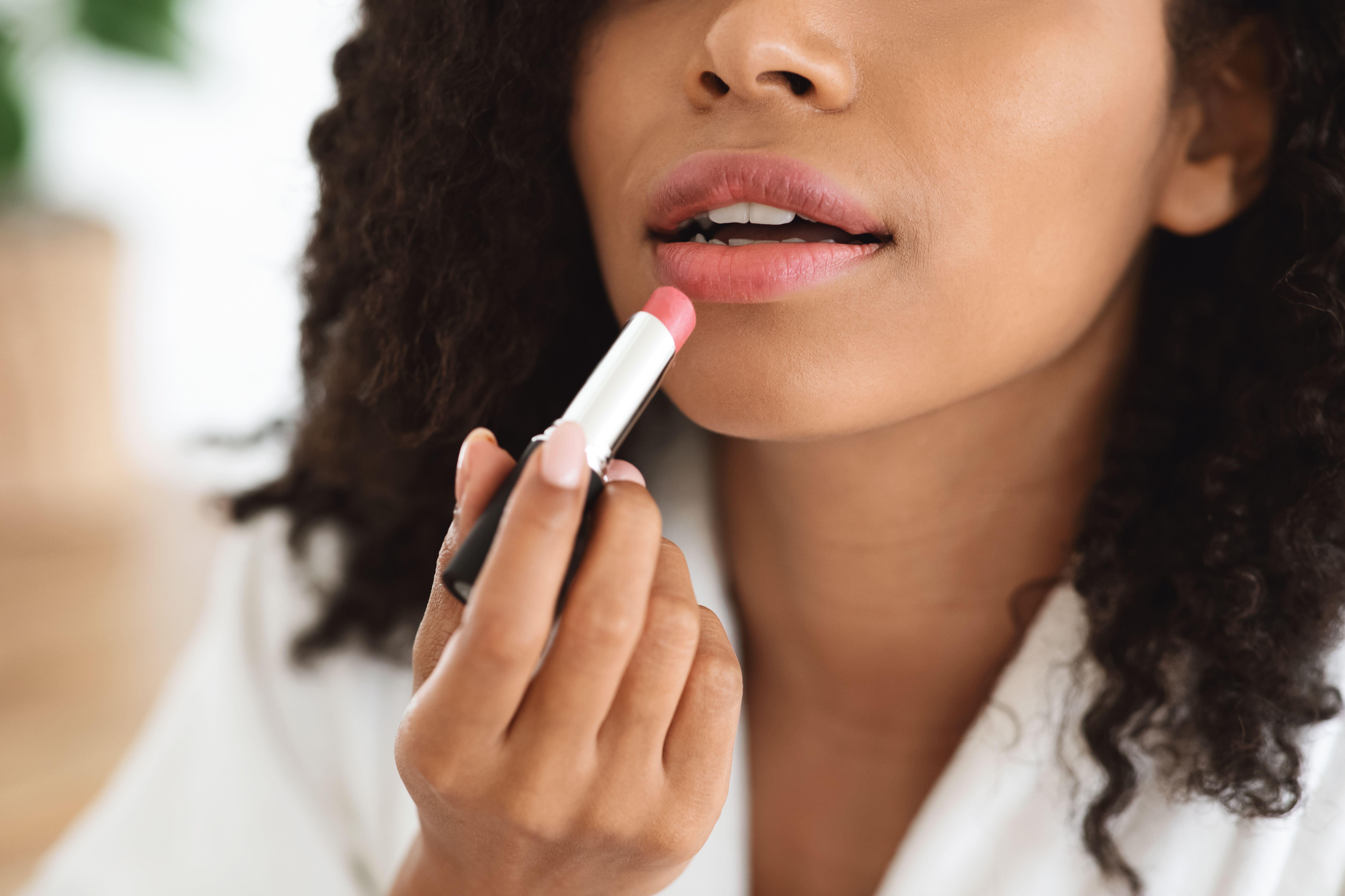 Closeup of woman applying pink lipstick