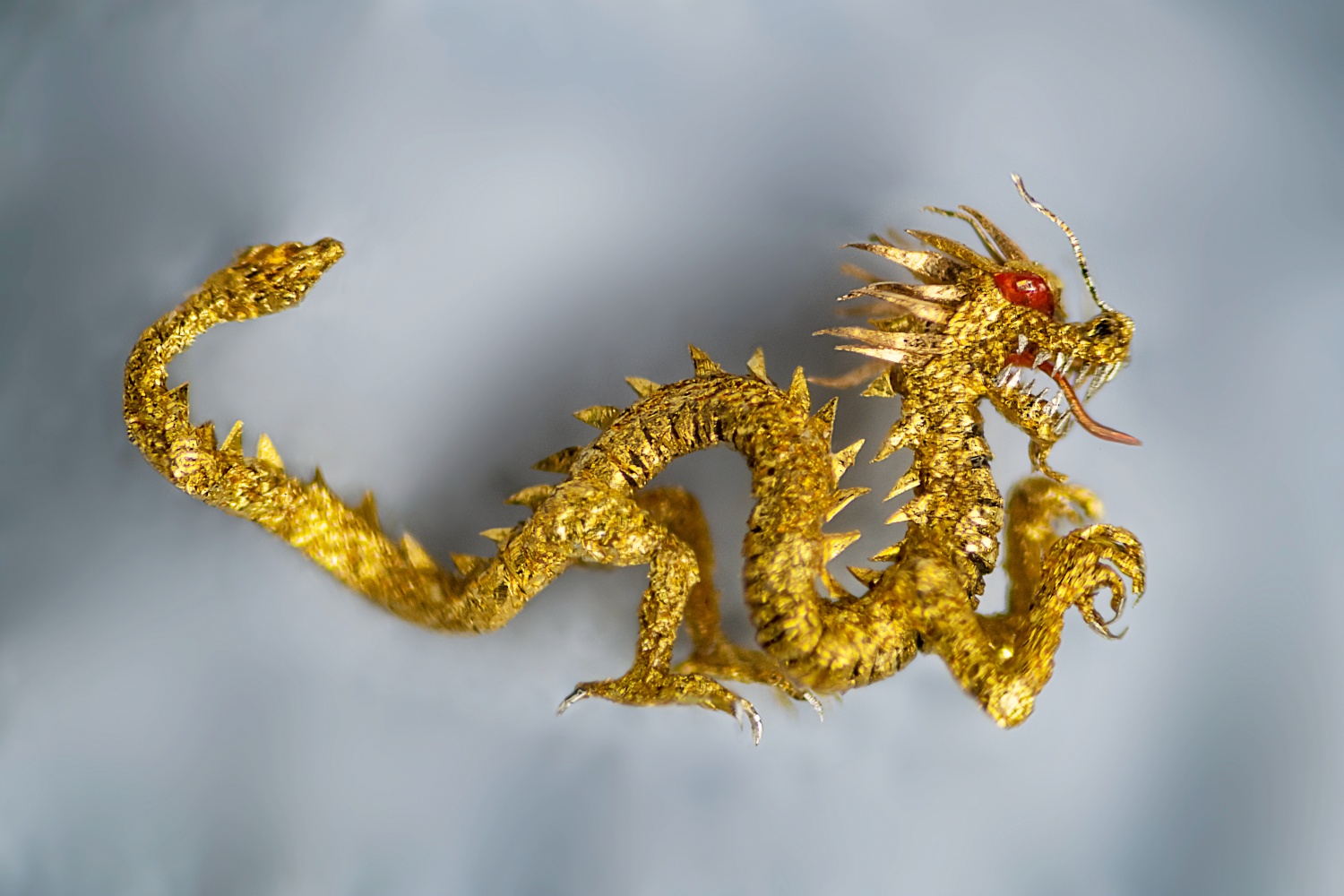 A zoomed in photo of a microscopic sculpture of a golden dragon