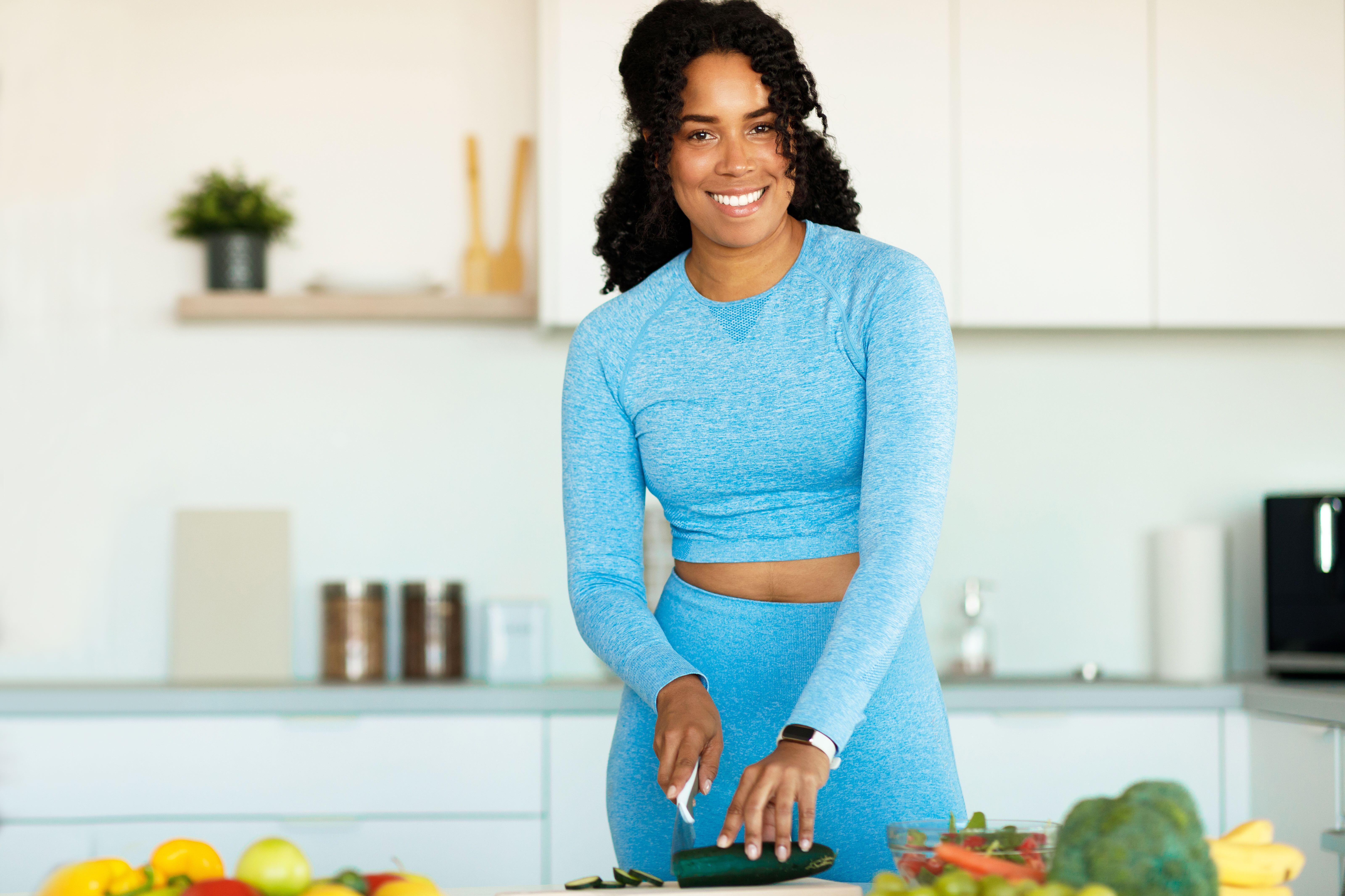 Young woman in fitness gear cooking a healthy meal