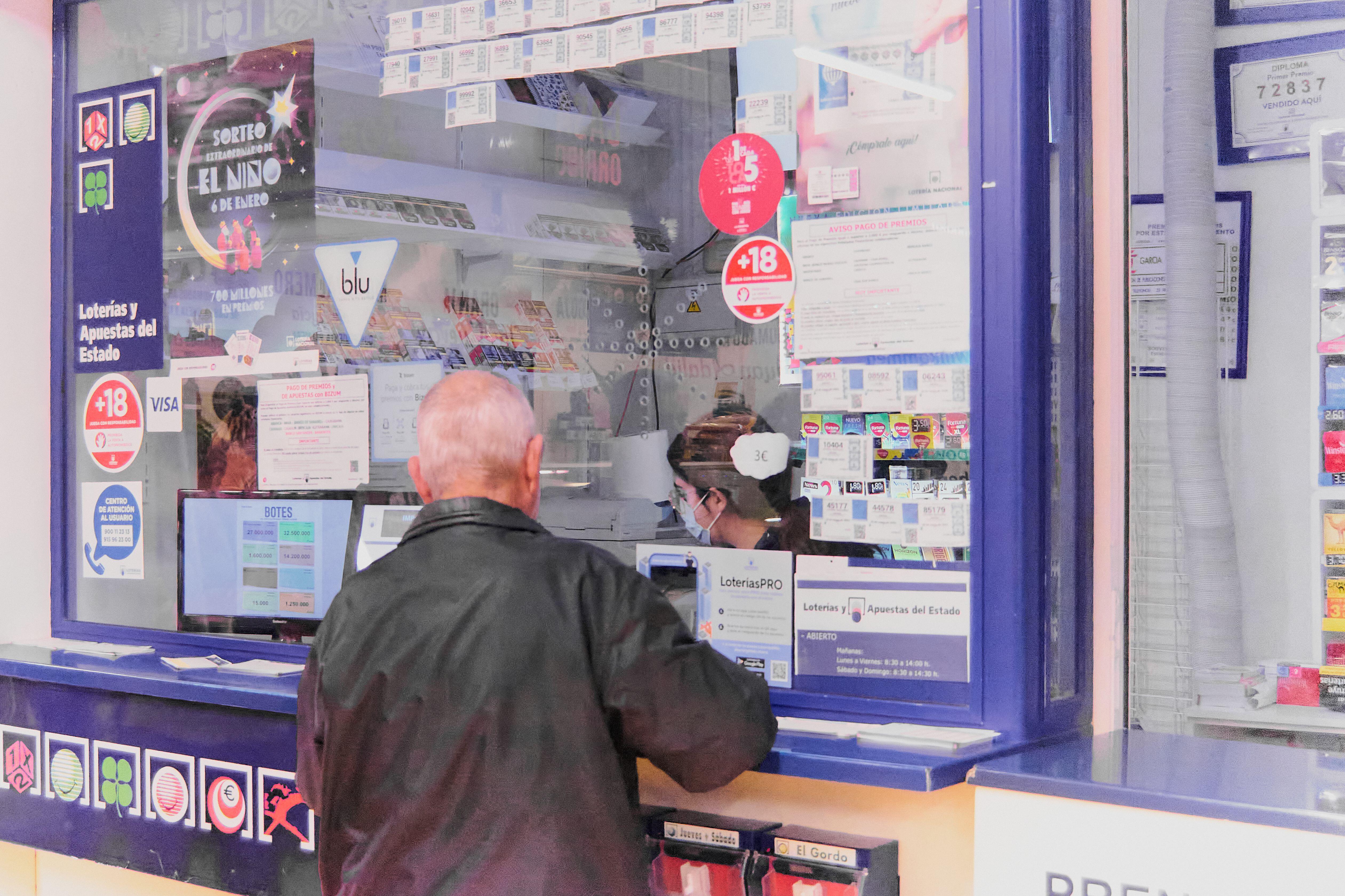2M75HT1 Tenerife, Spain - January 07, 2023: Unrecognizable elderly person in front of a lottery stand buying lottery tickets attended by a woman