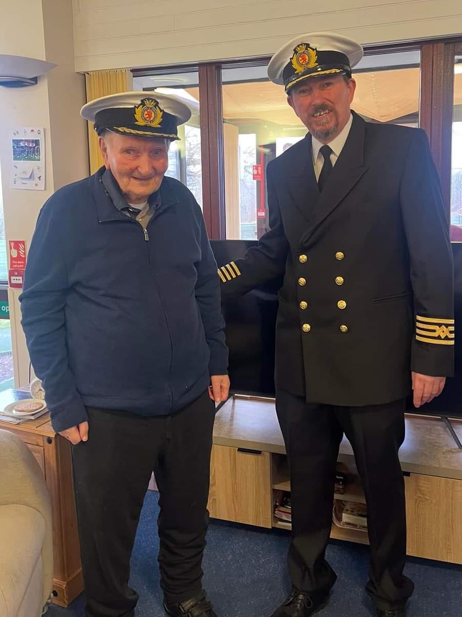 "Dolan" is pictured with CalMac's Captain Iain McKenzie from MV Loch Nevis sporting their matching captains hats