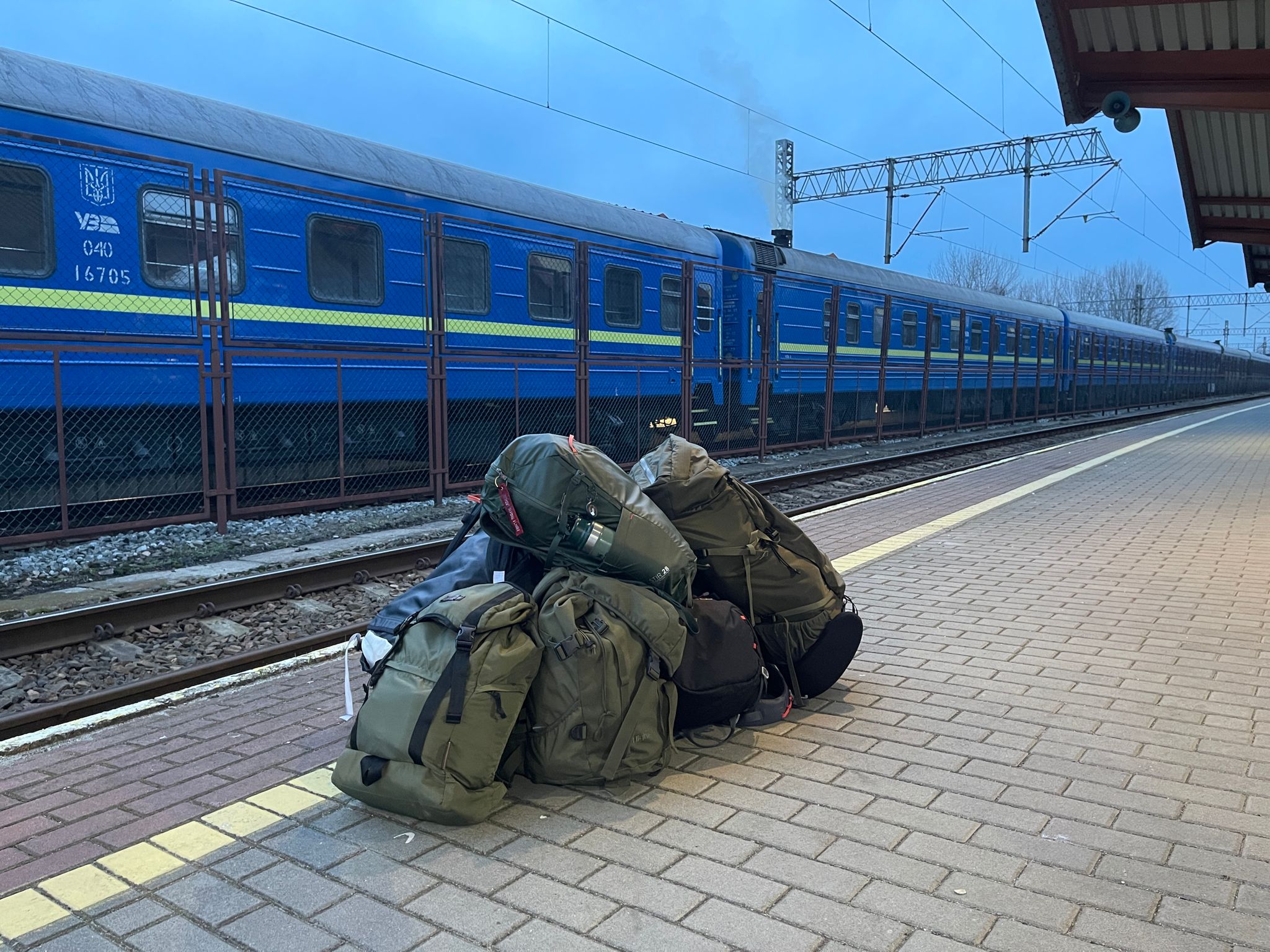A photo of rucksacks and sleeping bags on a train platform in Ukraine