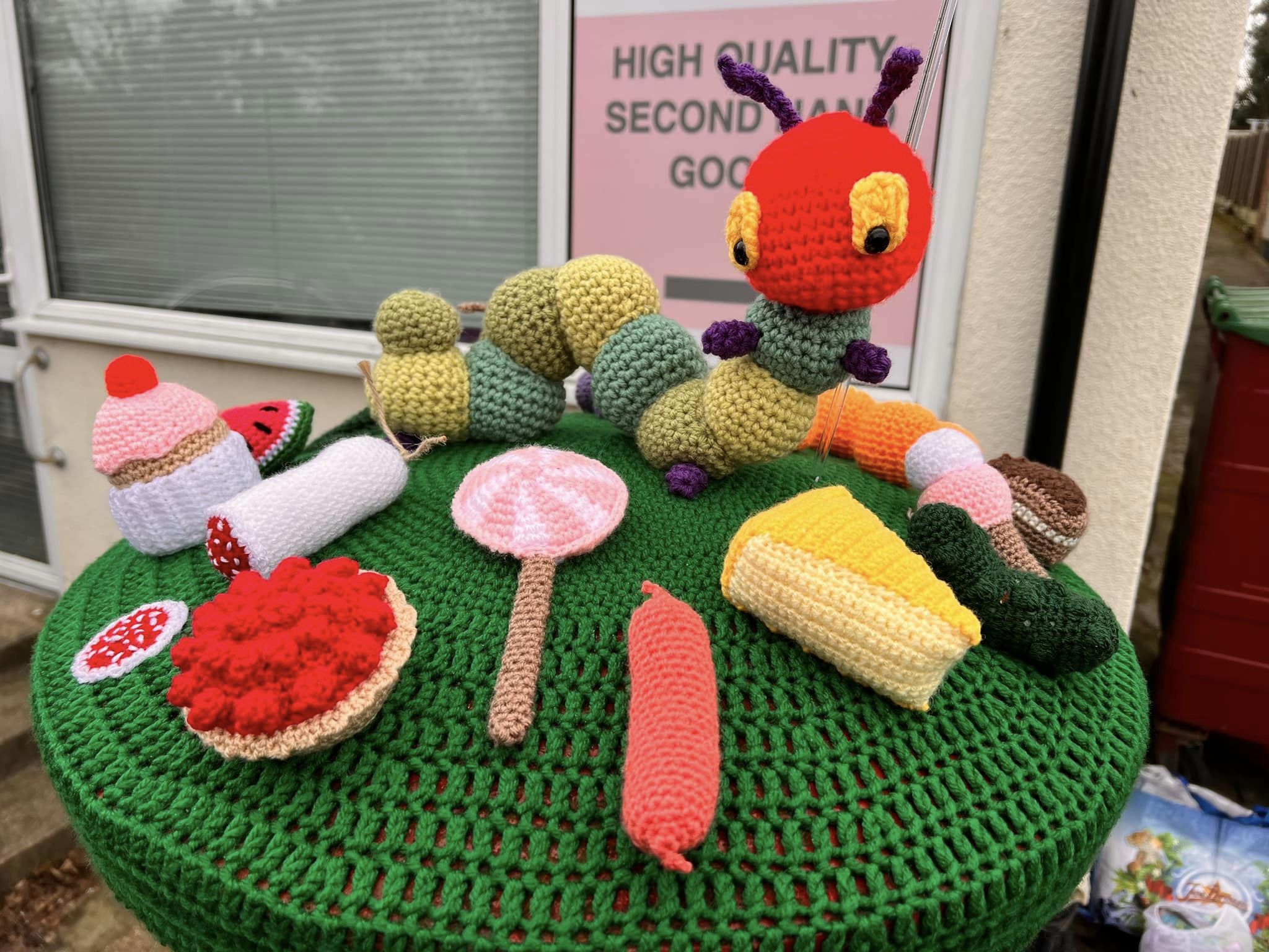 Crocheted caterpillar and food on top of postbox 