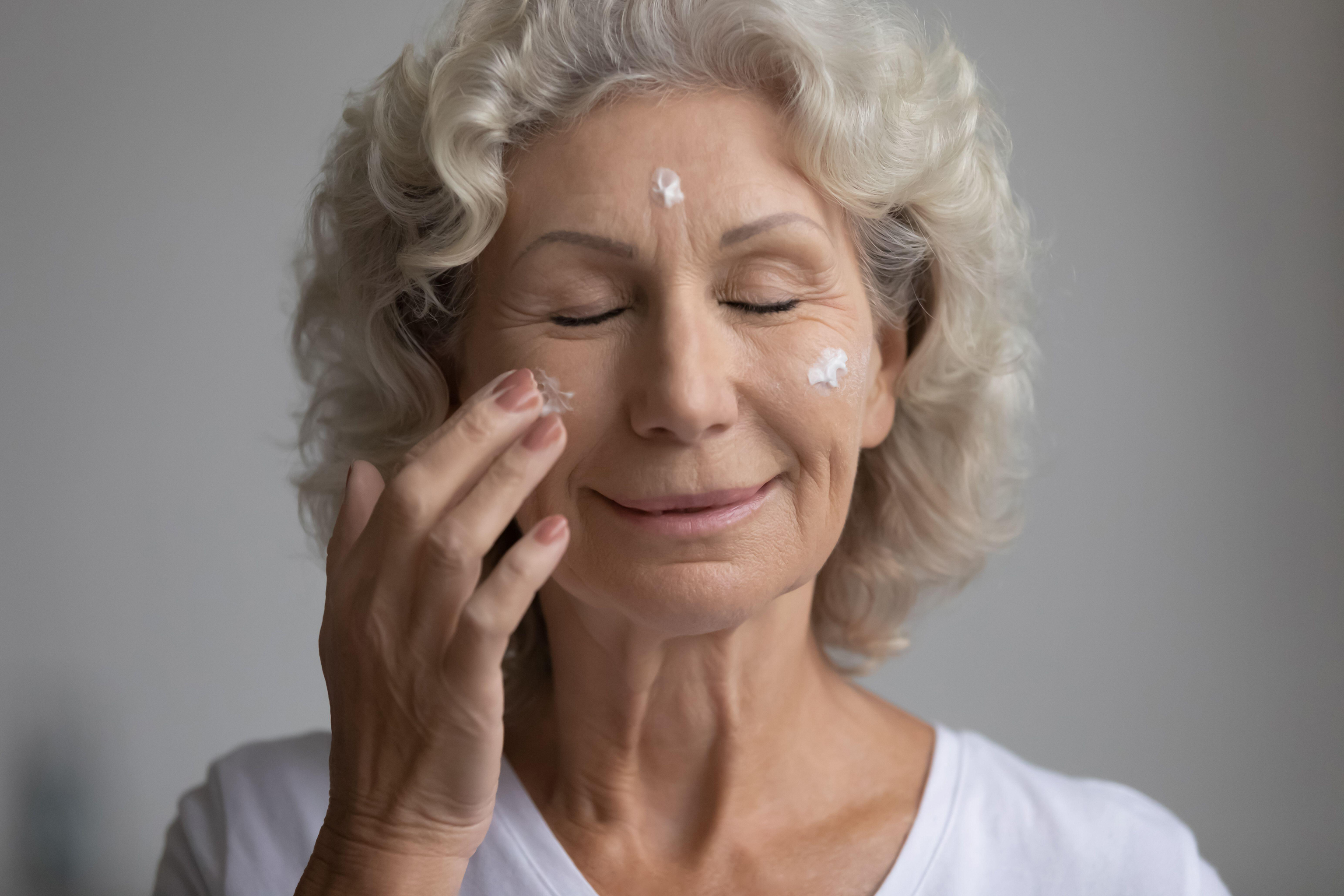 Older woman applying moisturising face cream