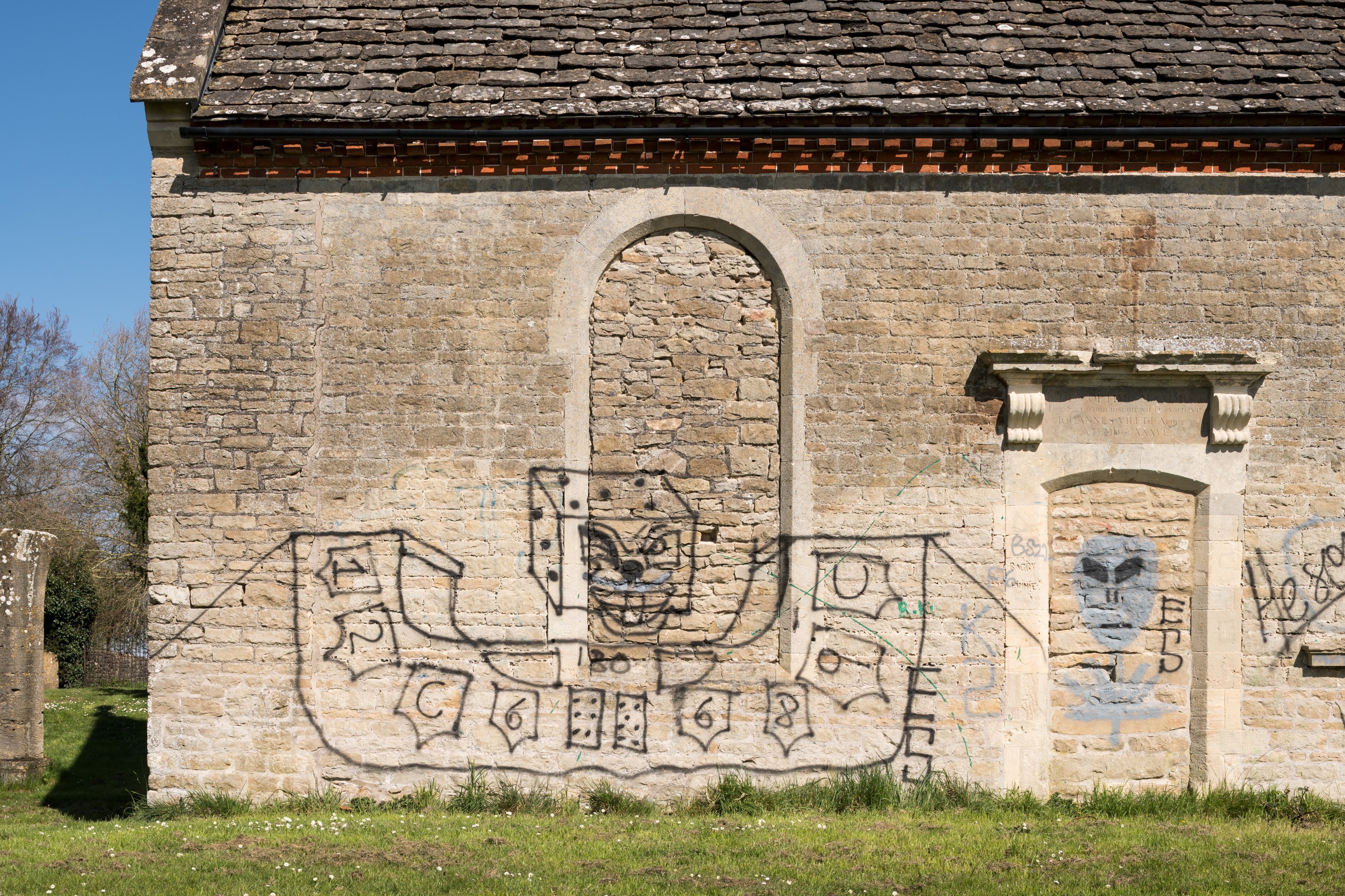 Graffiti on the side of an old stone building, Holy Rood Chapel in Swindon, Wiltshire.