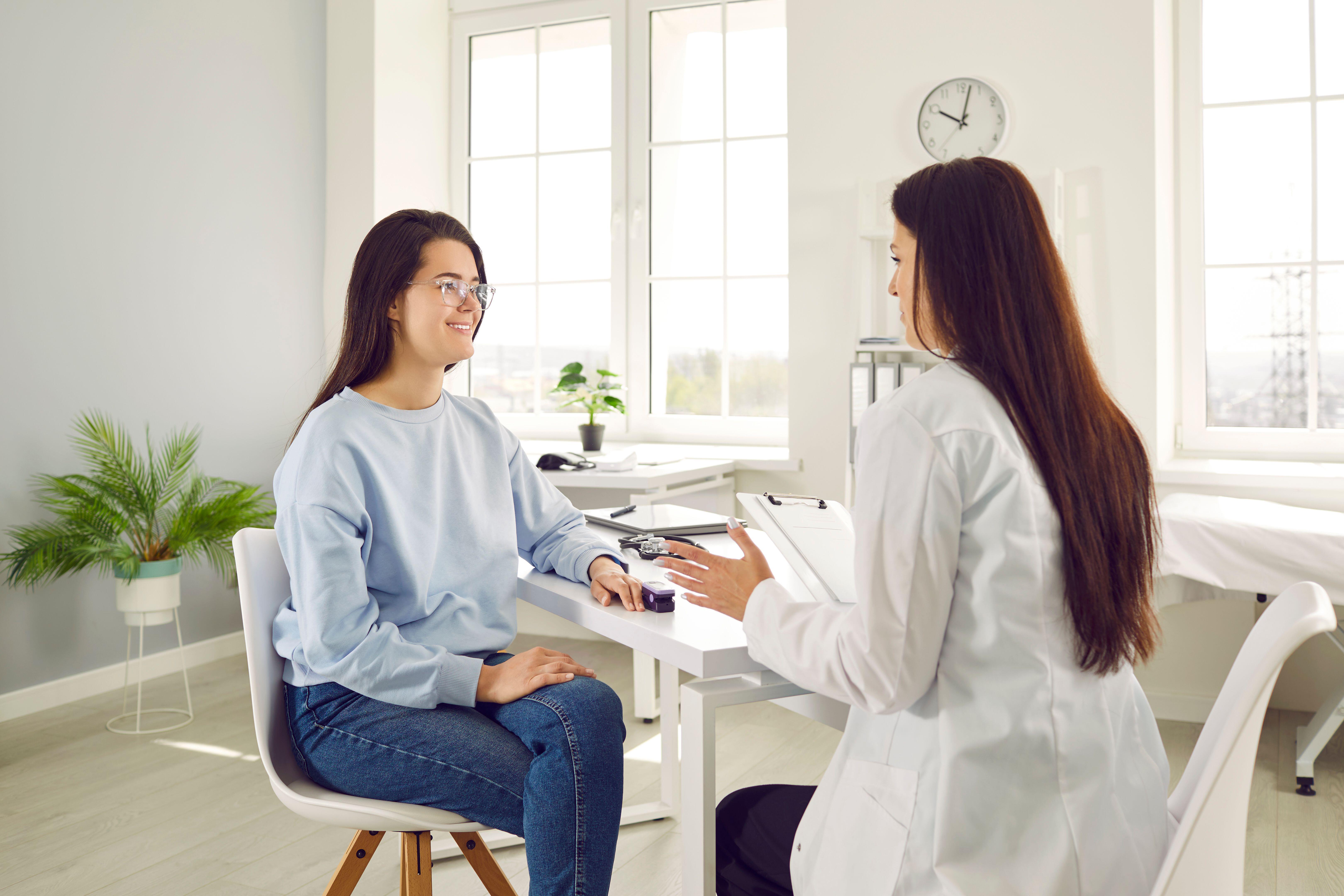 A woman having her heart rate measured while talking with a doctor