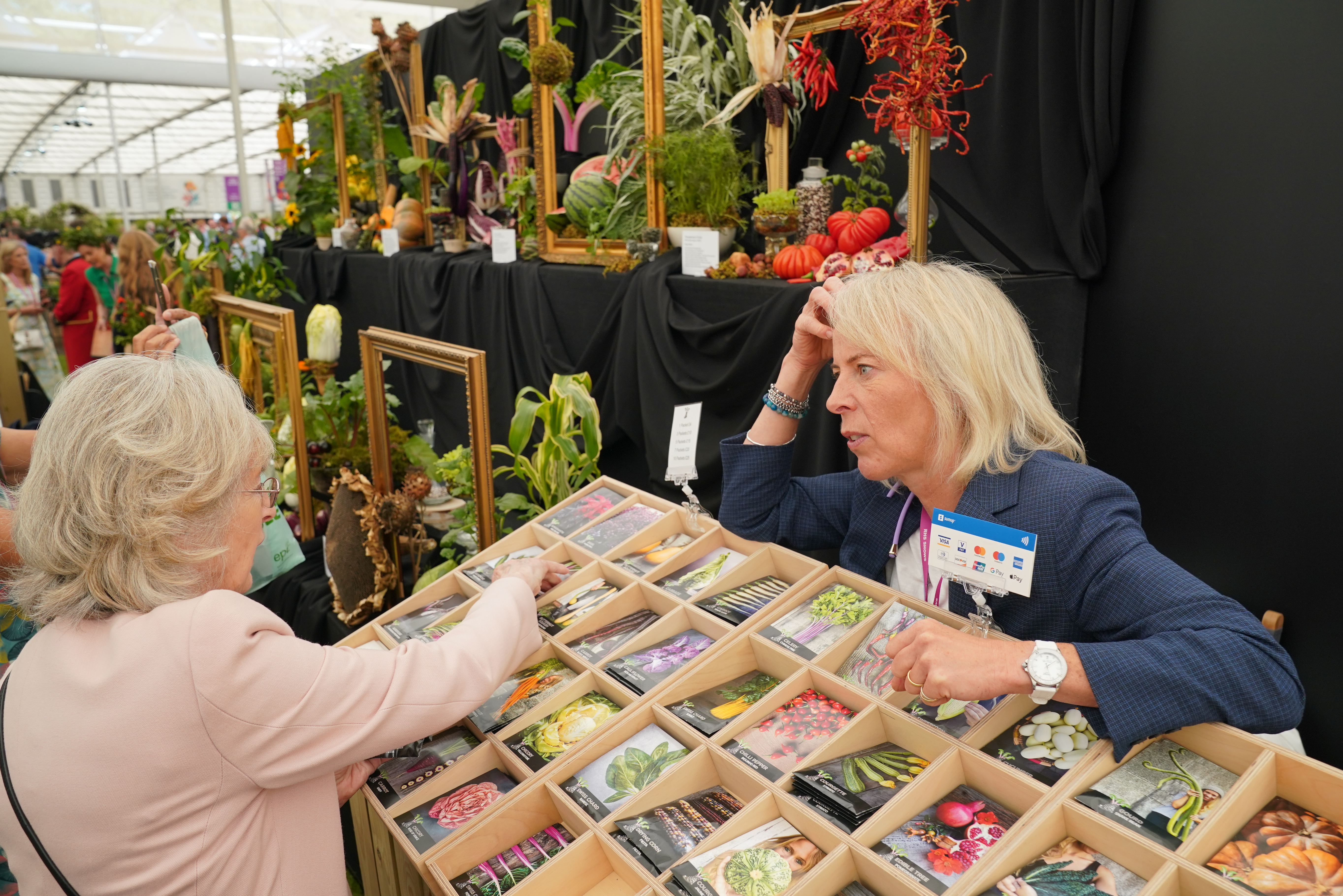 A visitor speaking to someone about seeds and growing their own vegetables at a display in the Grand Pavillion during the RHS Chelsea Flower Show at the Royal Hospital Chelsea in London.