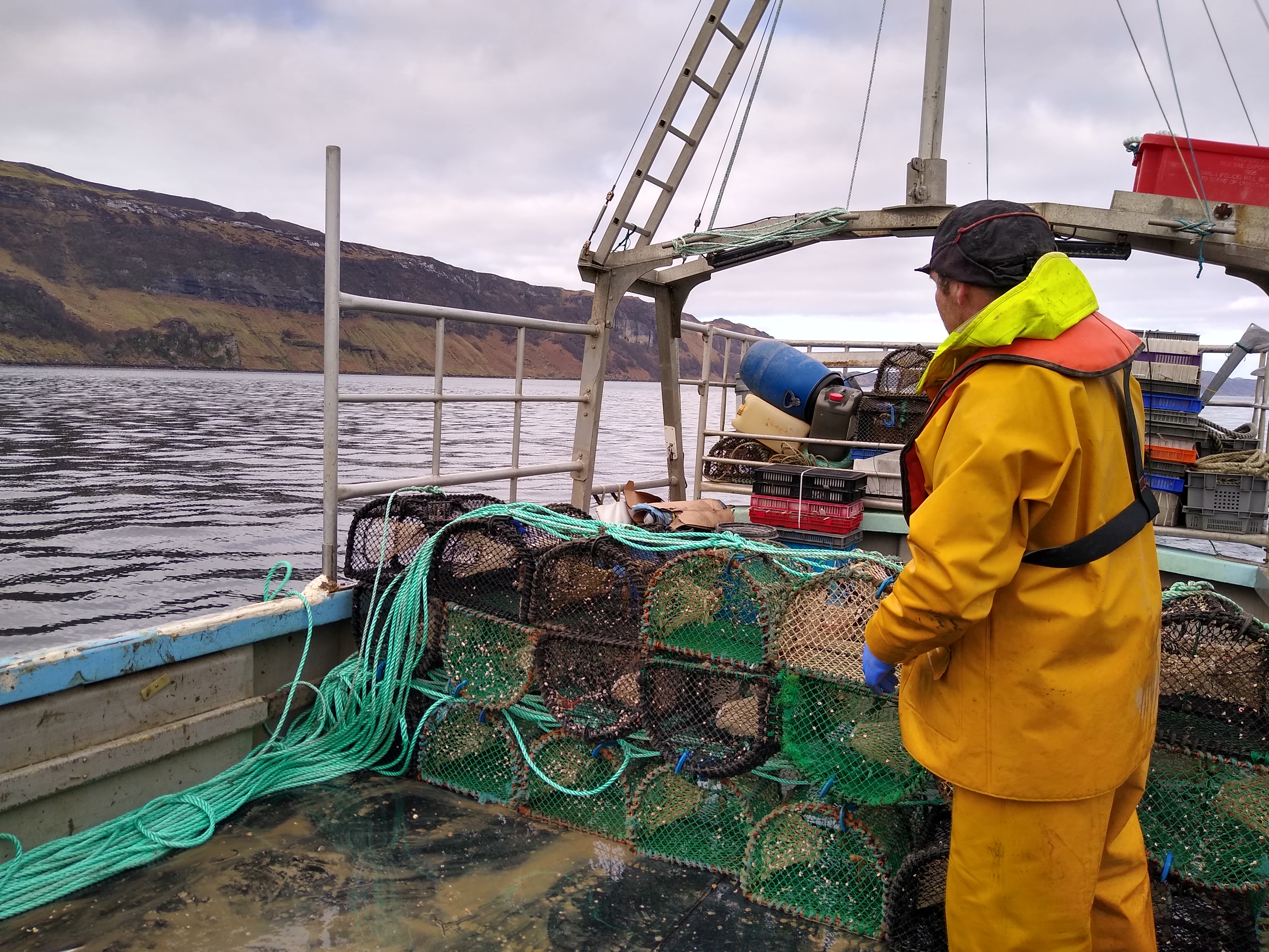 A fisher standing by creels and the new fishing rope on a vessel