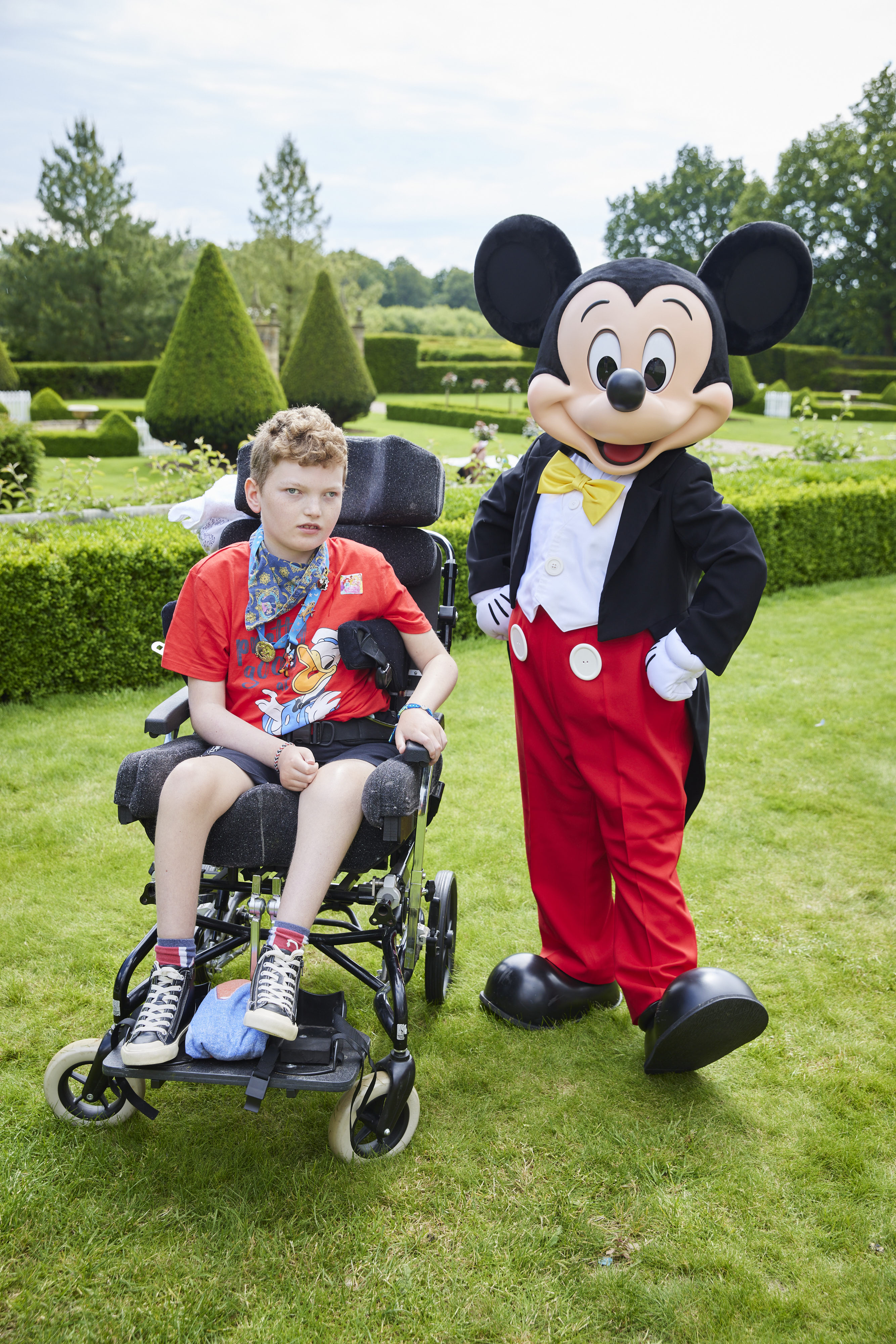Boy in wheelchair next to man dressed as mouse 