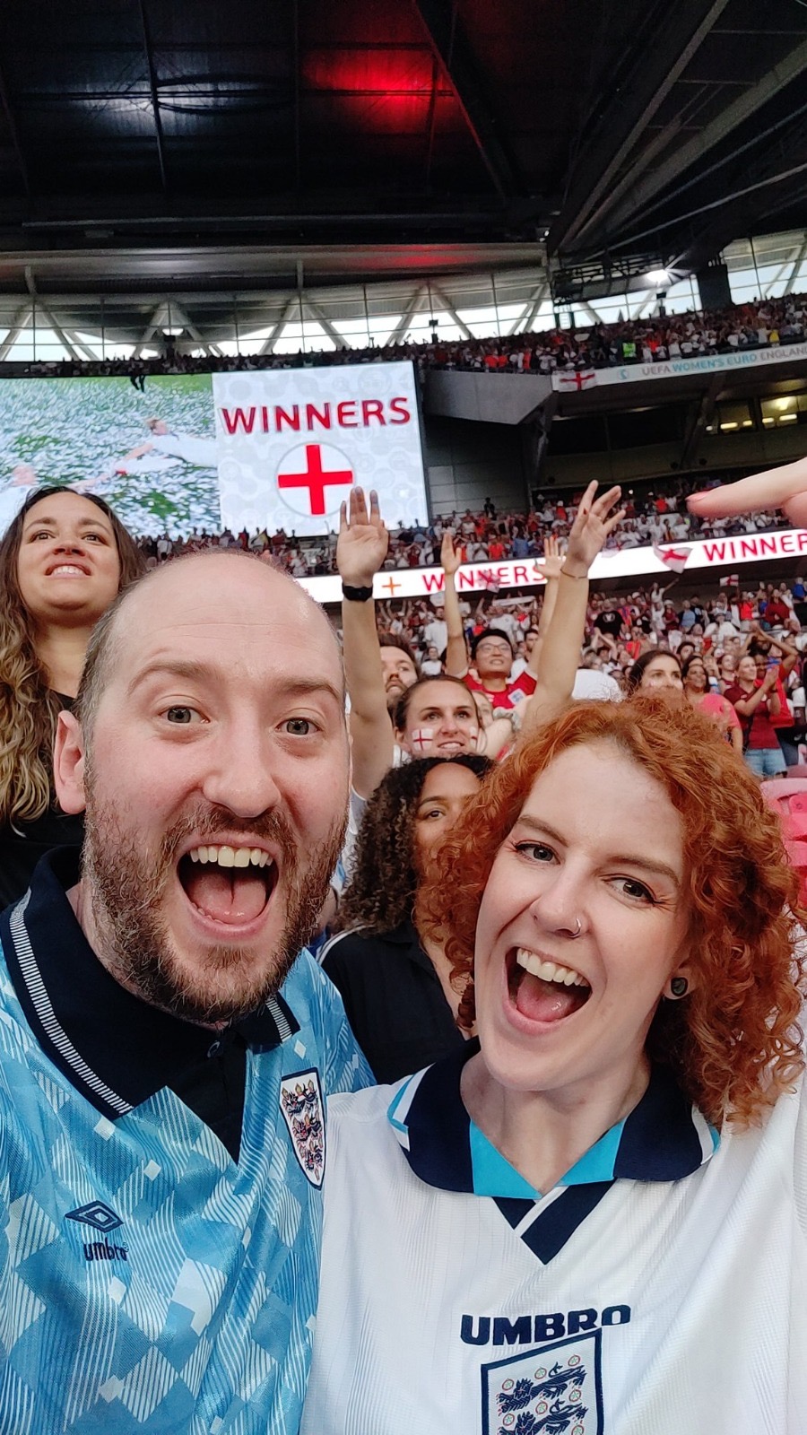 Gus Hully with his wife, Kimberley Robertson, celebrating in a stadium during the Women's Euro in 2022