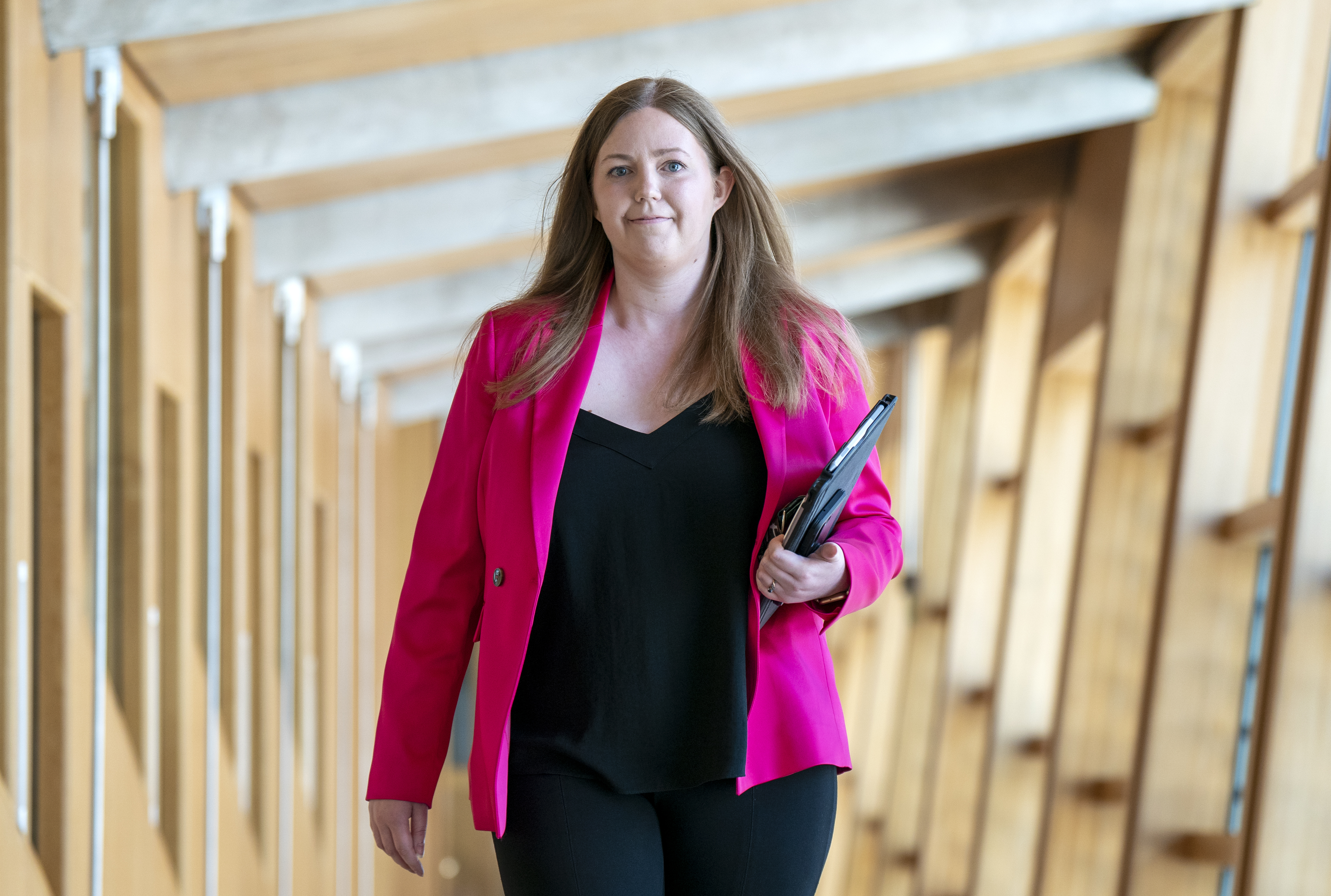 Gillian Mackay smiling while walking through a corridor at Holyrood