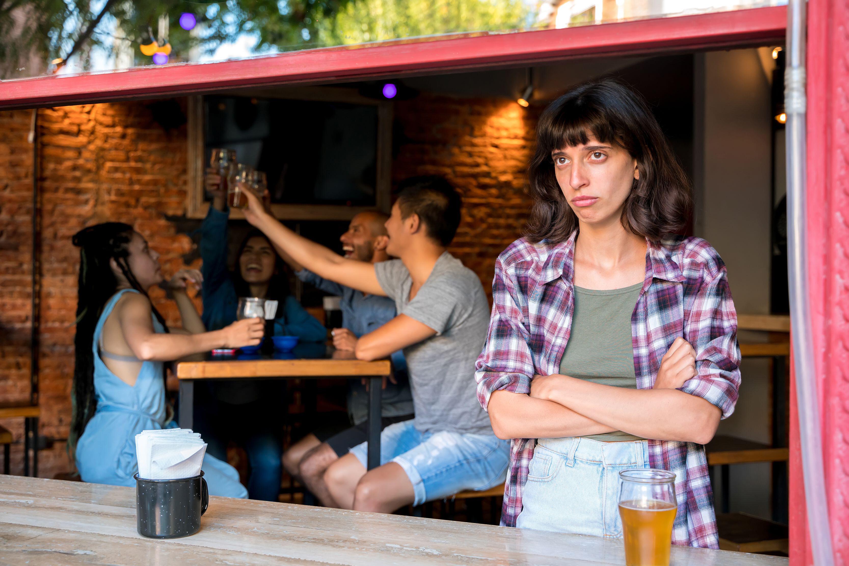 2C85RK8 A young latin woman being excluded by her friends in a bar or pub.