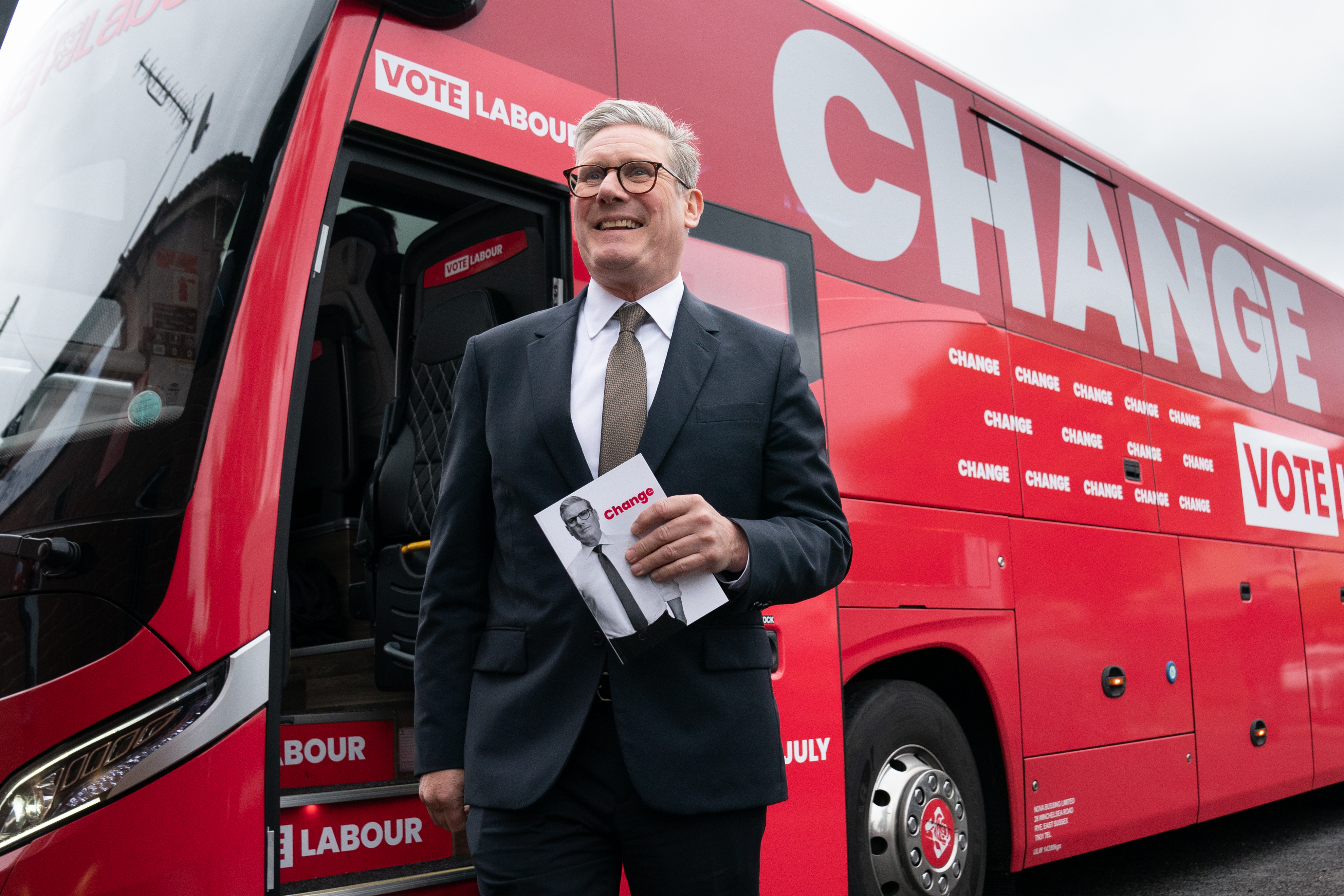Sir Keir Starmer holding a Labour manifesto in front of his battlebus