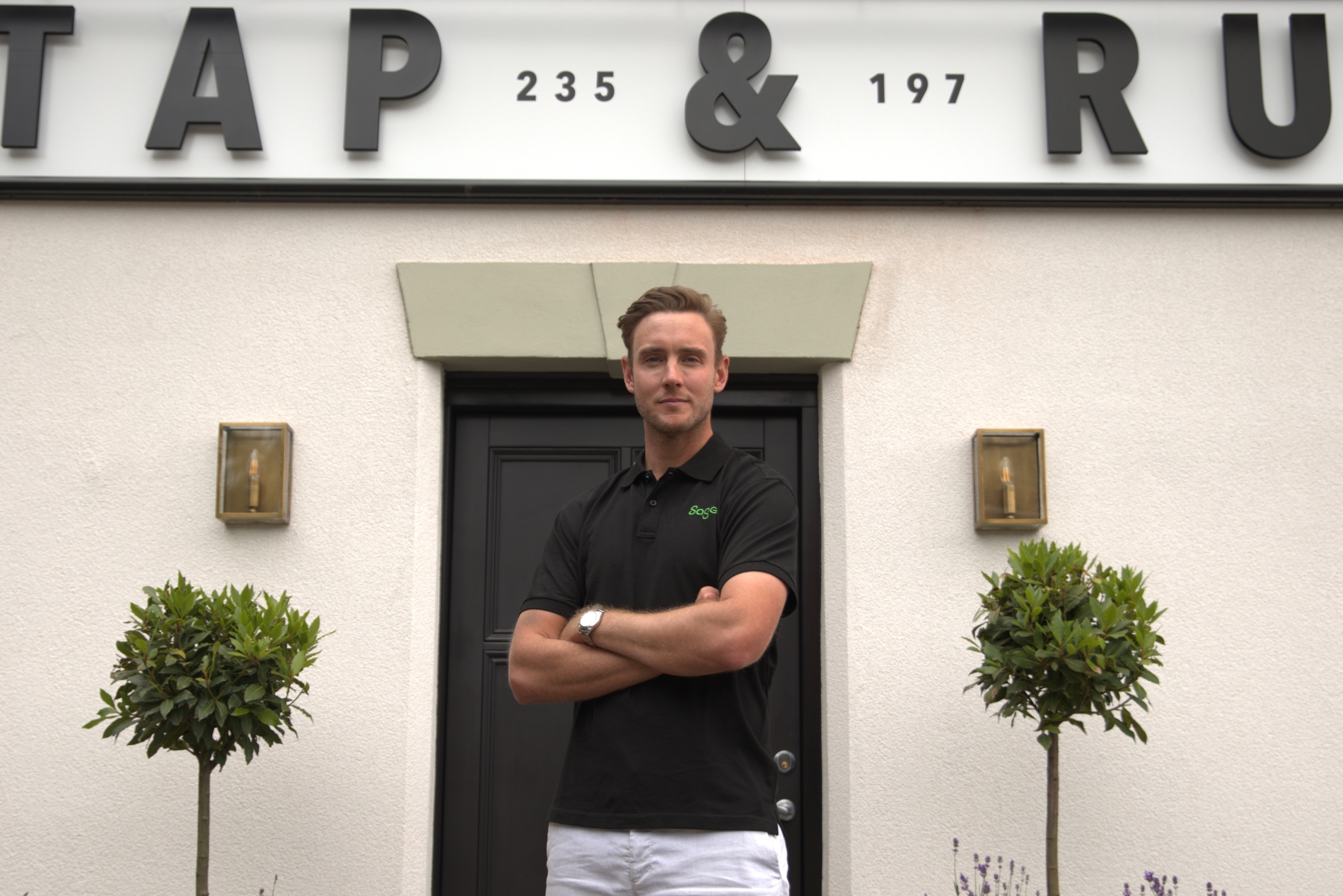 Former cricketer Stuart Broad stands outside the Tap & Run pub with his arms folded