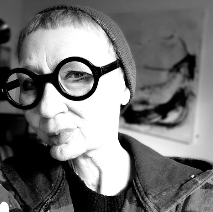 A black and white selfie of Jane Beesley wearing glasses and a beanie hat