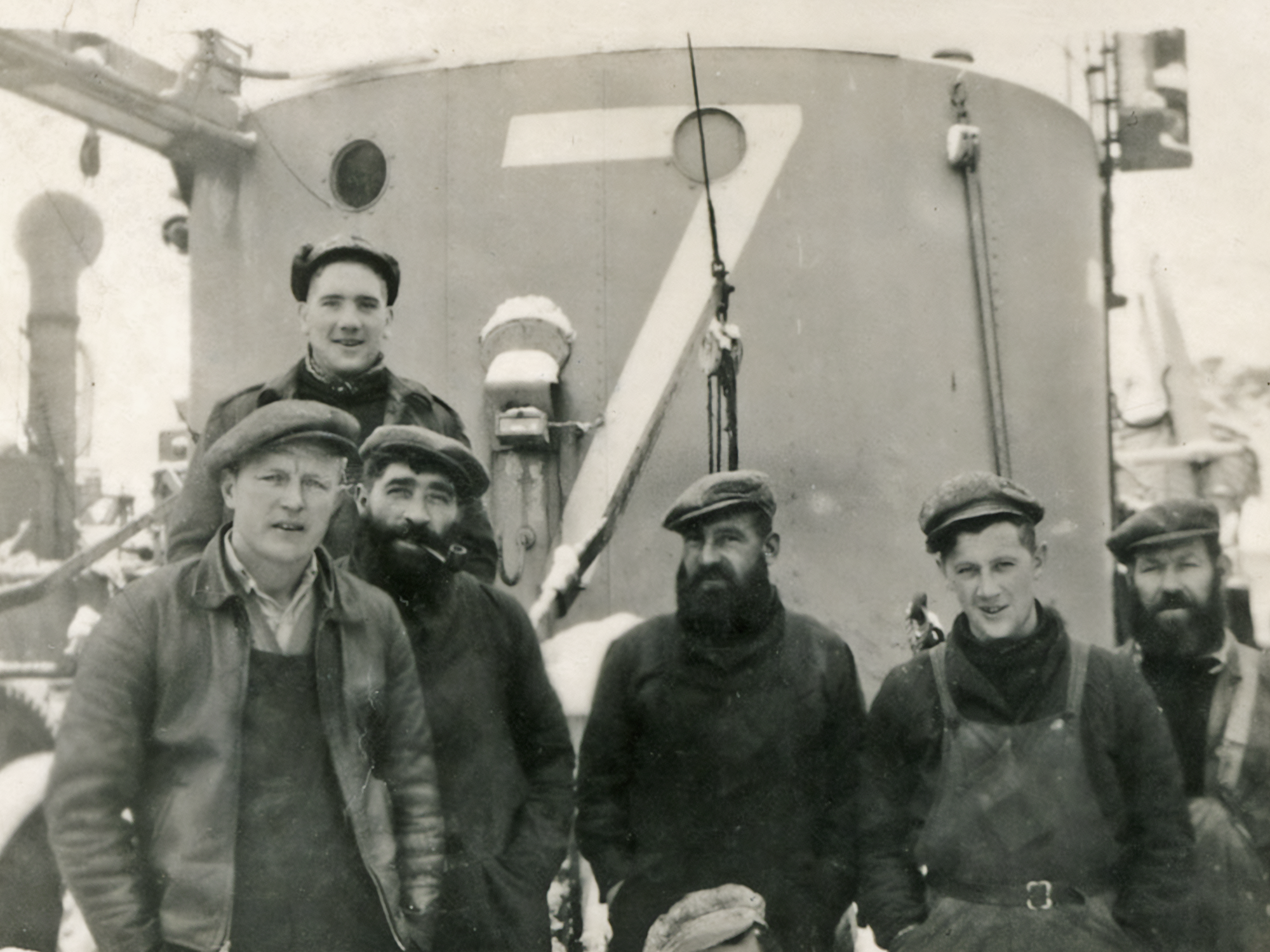 Black and white photo of six members of the crew on board a whaling ship