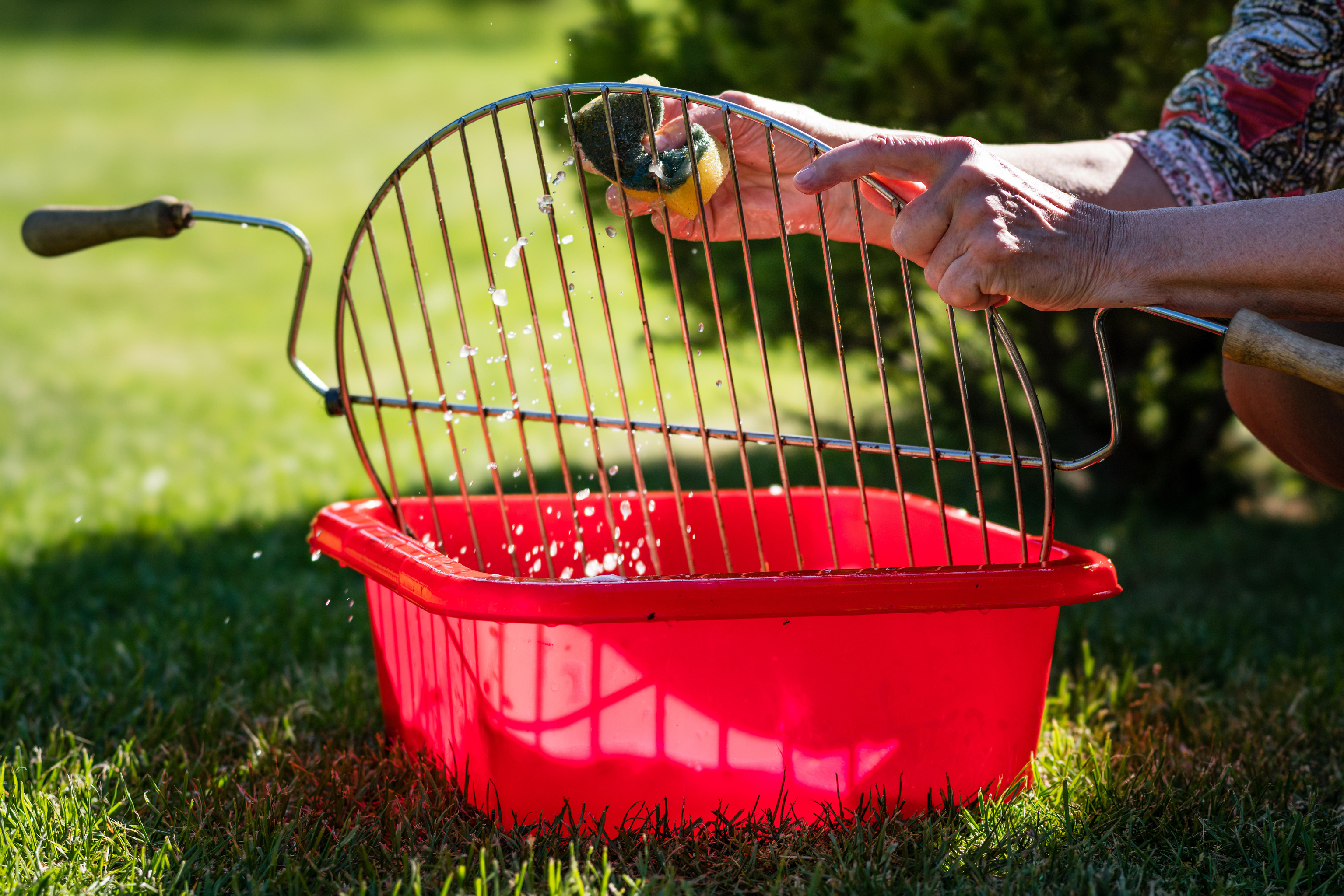 Woman cleaning BBQ grill