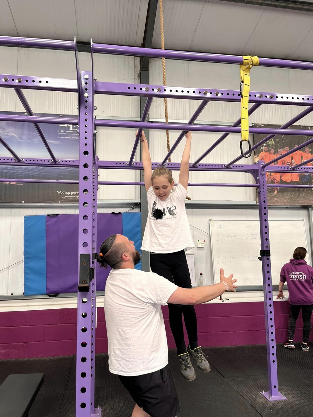 Girl on monkey bars being held up by a man 