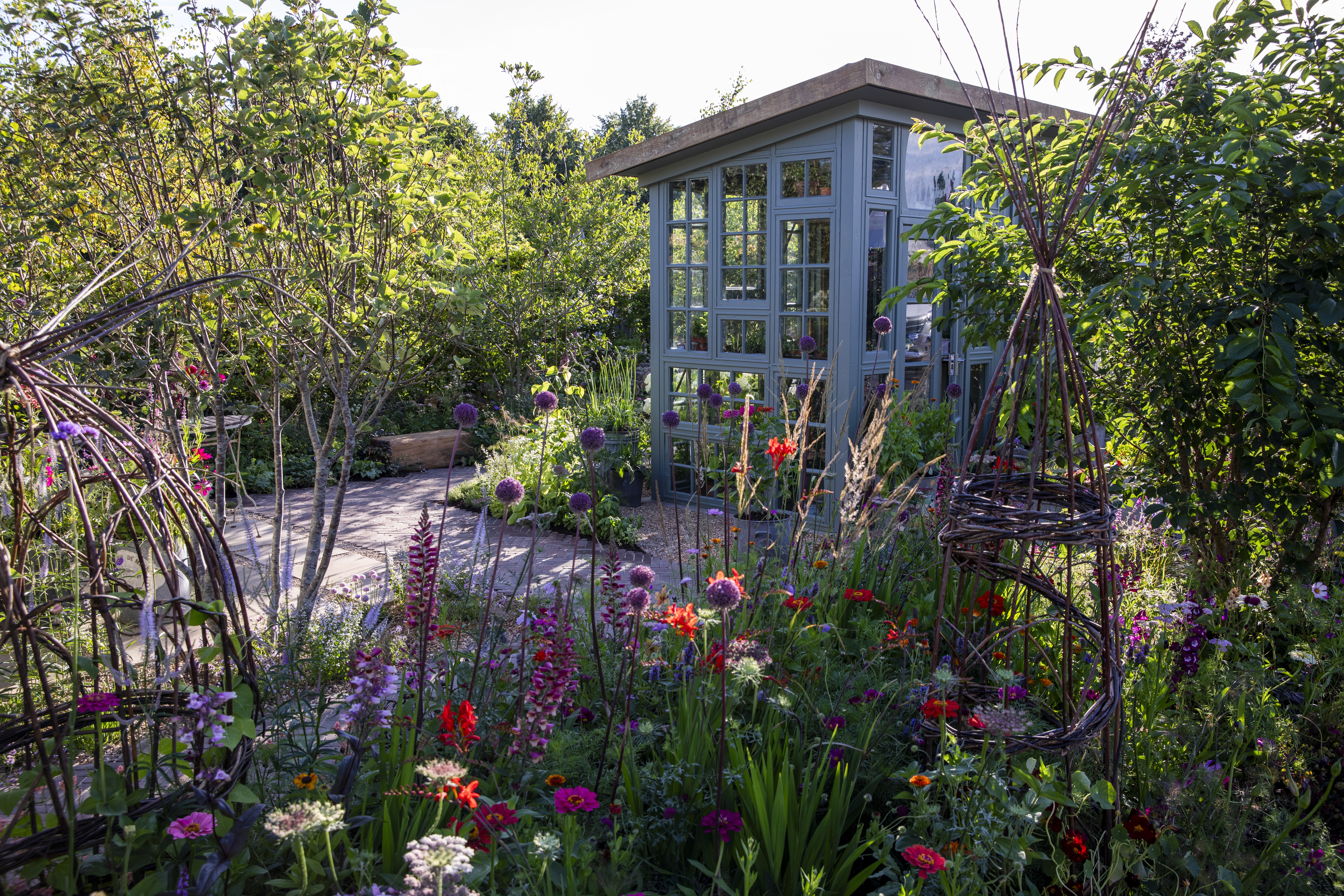 A greenhouse surrounded by flowering plants at the peat free garden