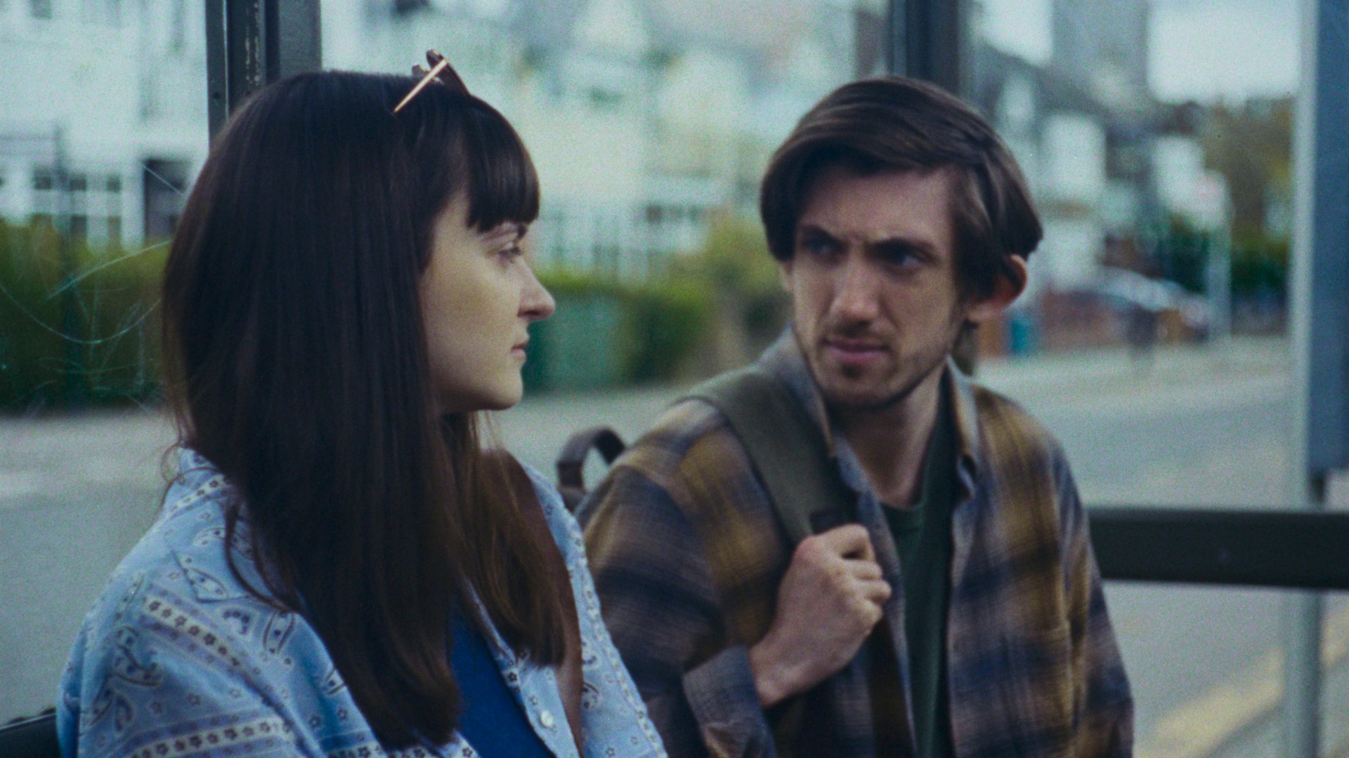 Two people sitting at a bus stop