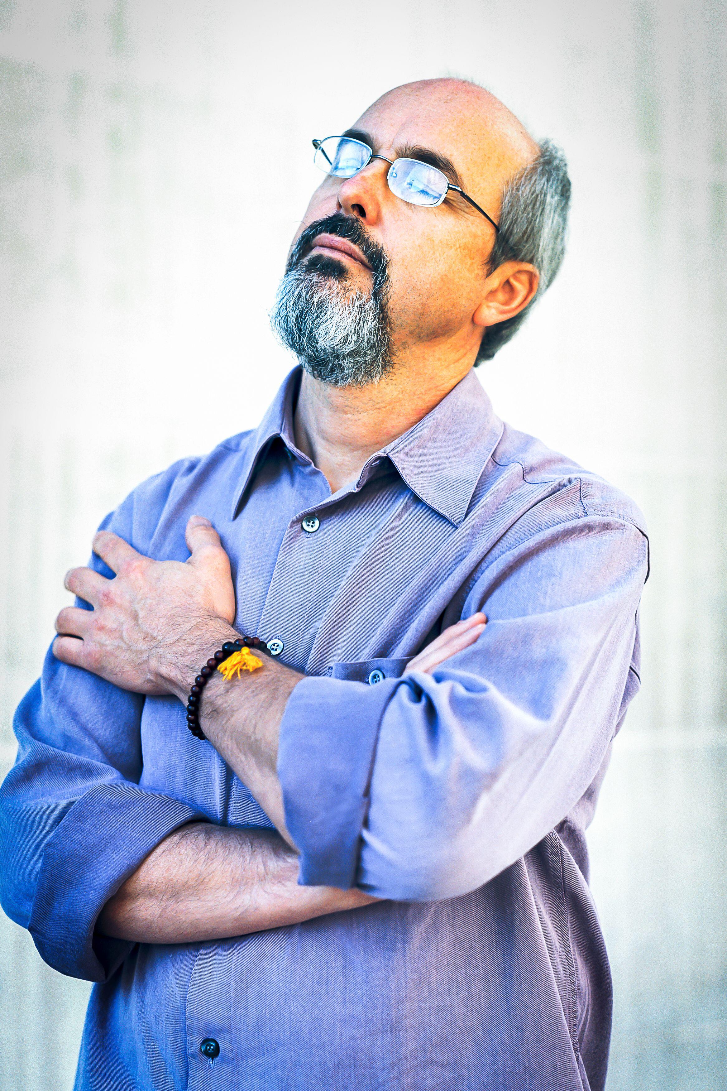 A man with a beard and glasses wearing a blue shirt