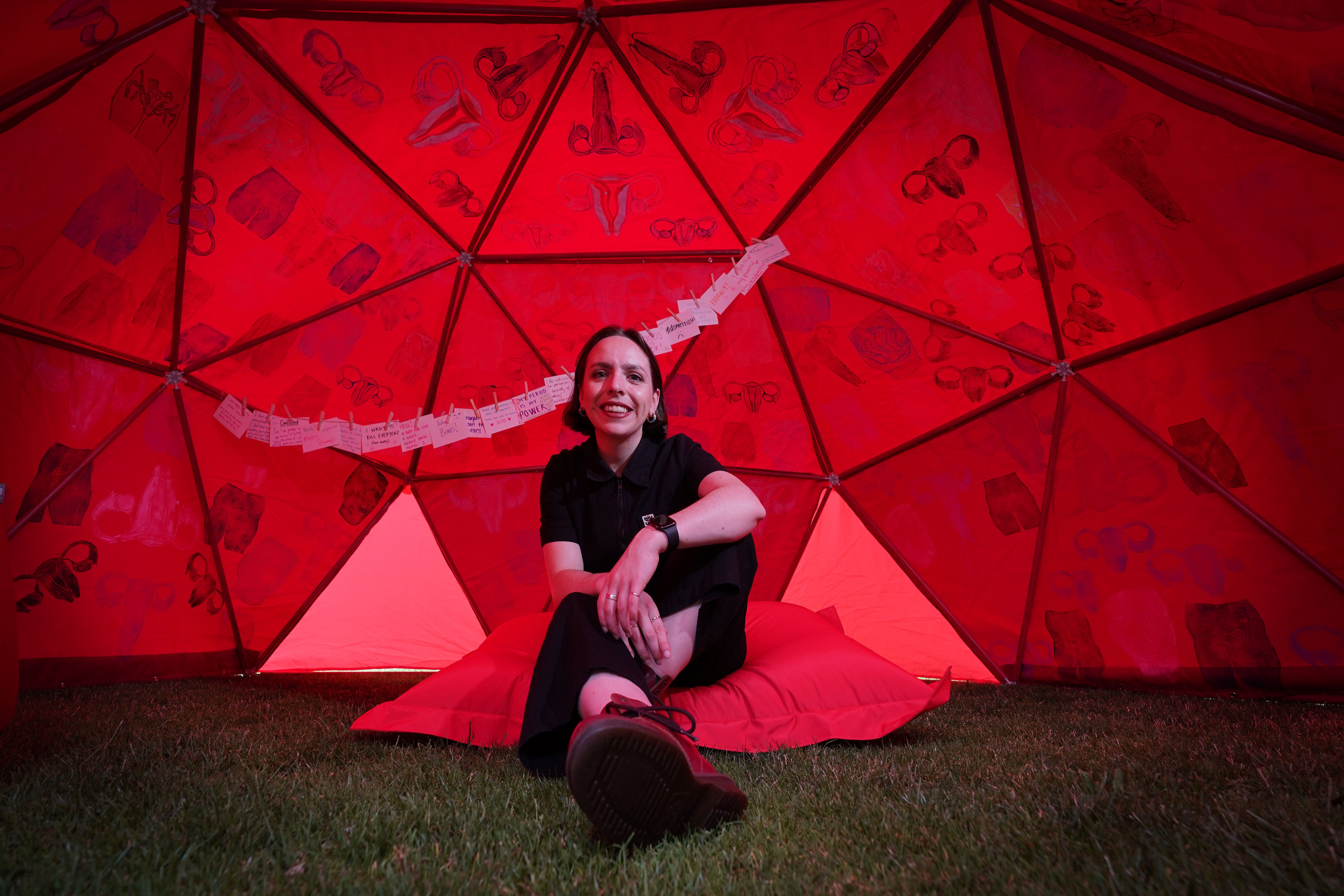 Francesca Hearn-Yeates sitting under her Wandering Womb exhibit