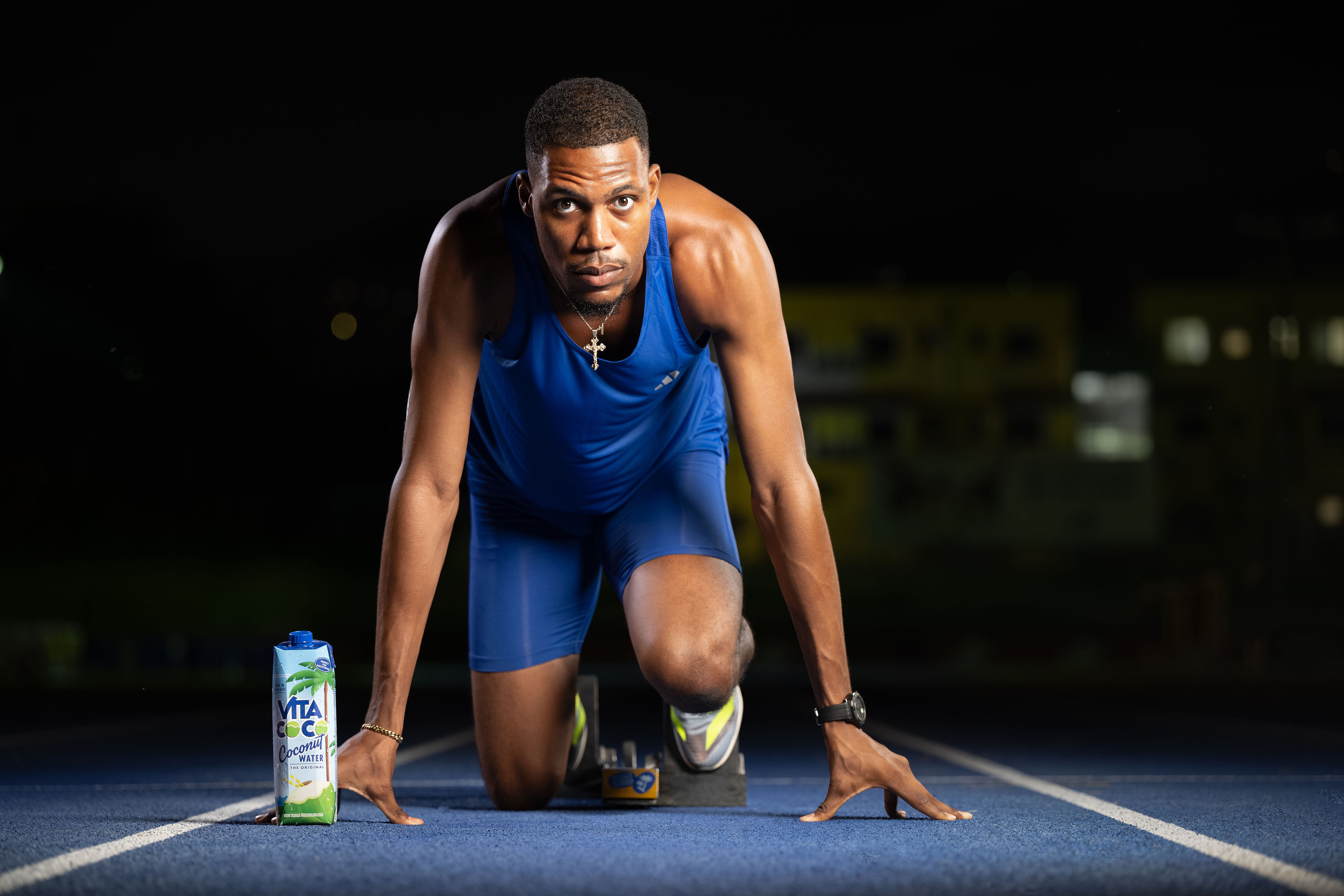 Zharnel Hughes in a start position in close-up, wearing a blue kit and staring directly at the camera