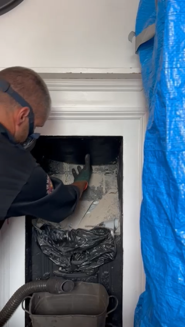 Chimney sweeps reaches for board inside flue