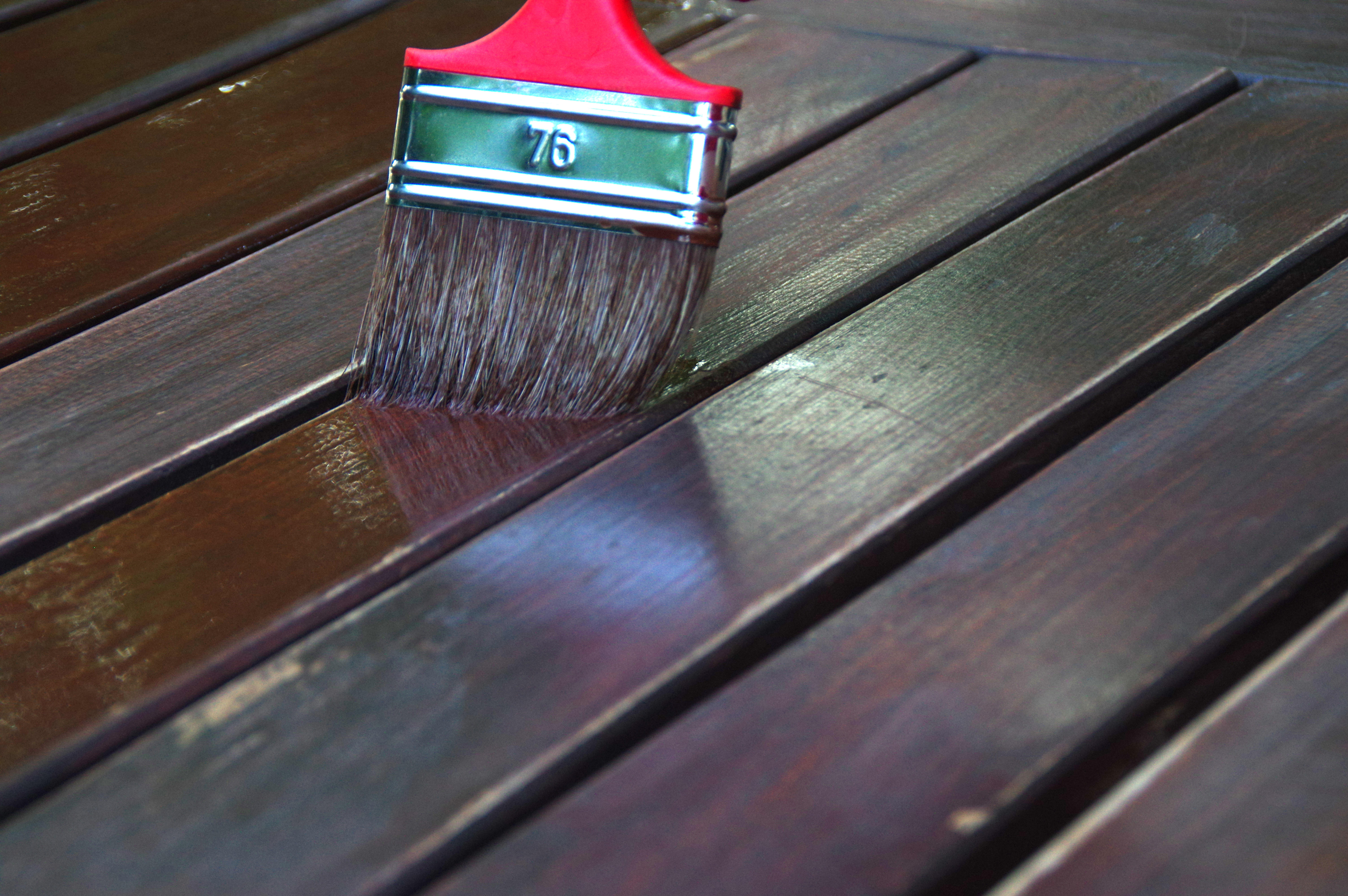 Person painting wooden garden table outdoors