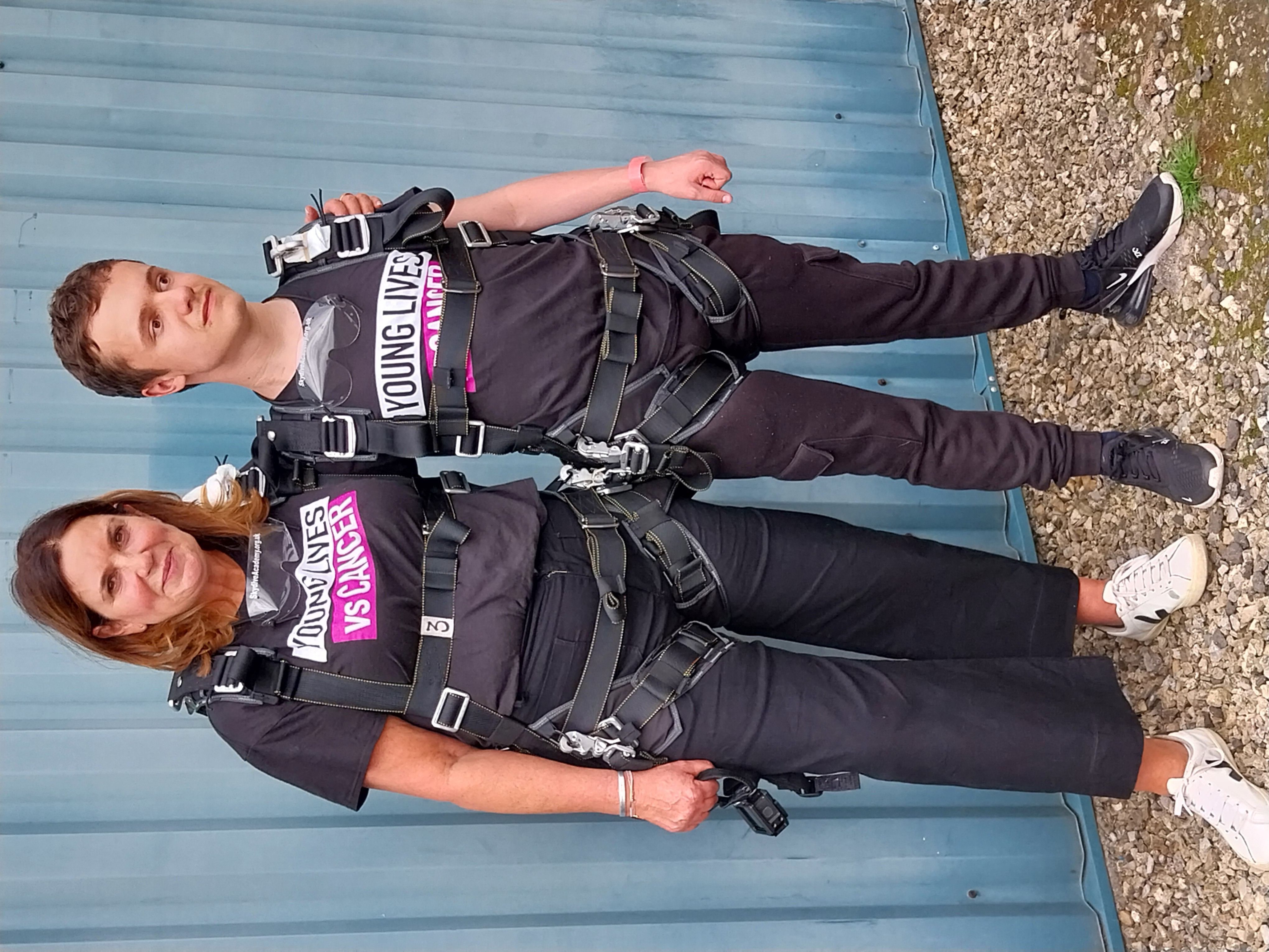 Two people standing together in skydiving equipment 