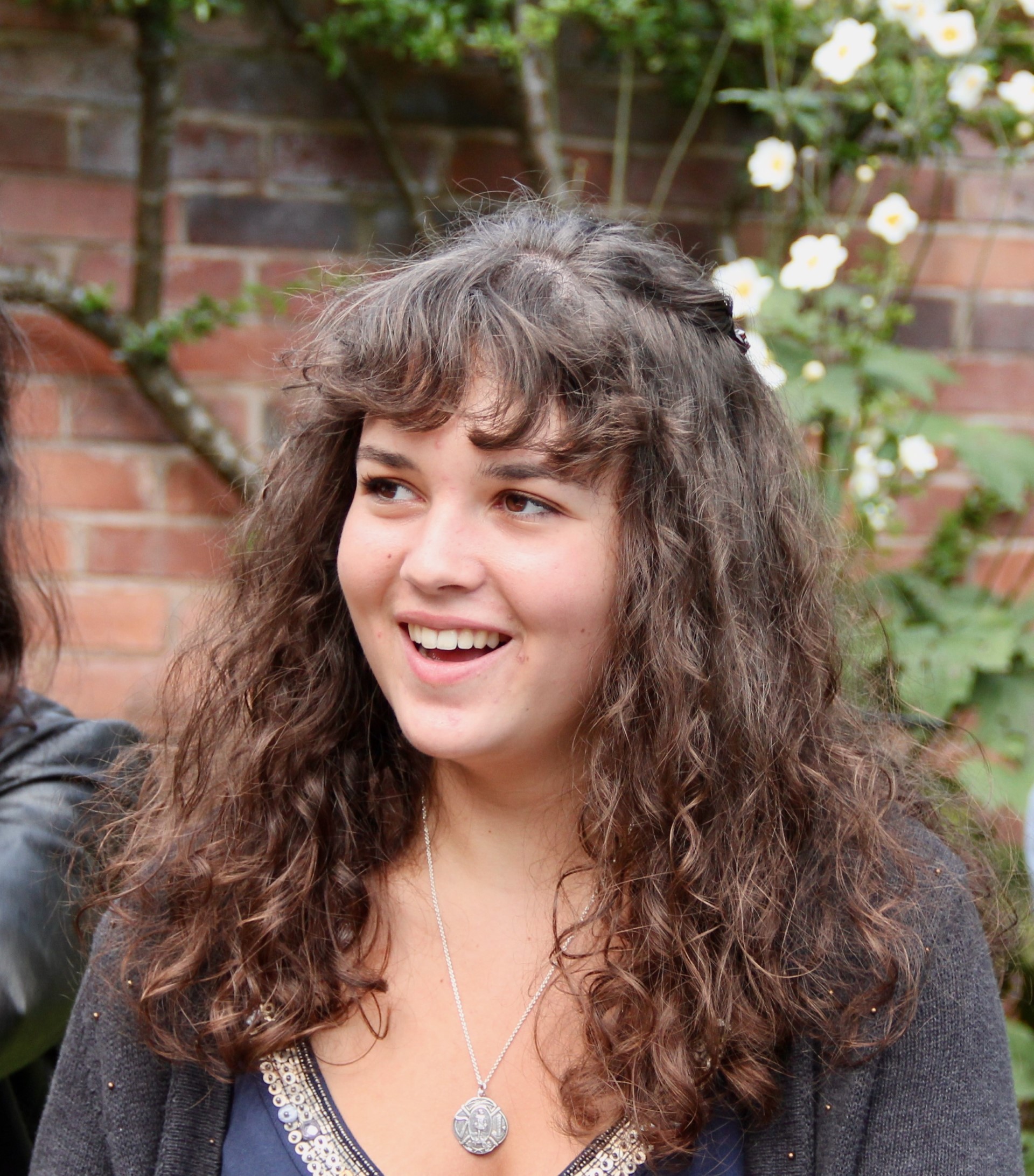 Head shot of a young woman with long dark curly hair