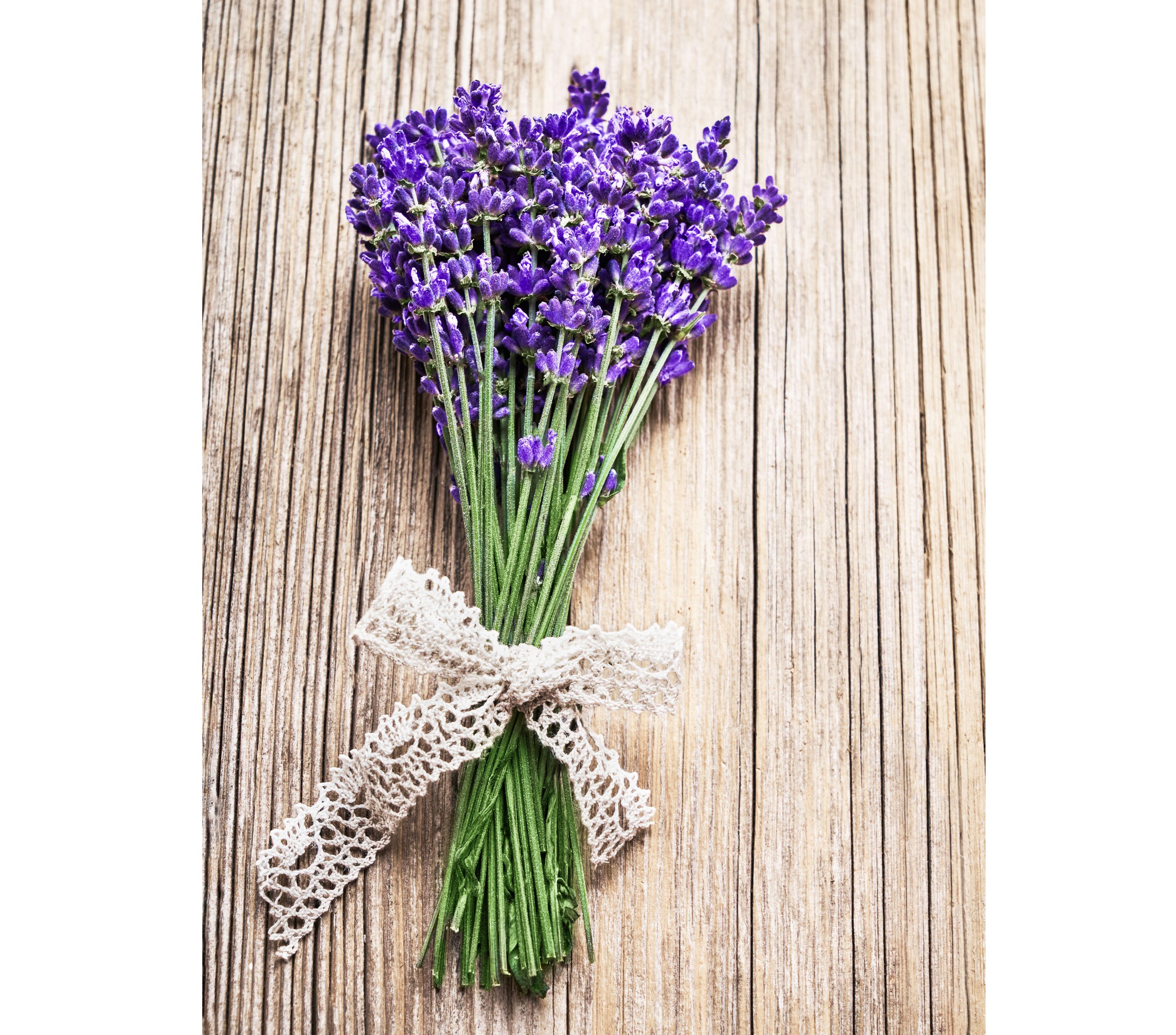 Bouquet of lavender flowers decorated with lace on wooden background