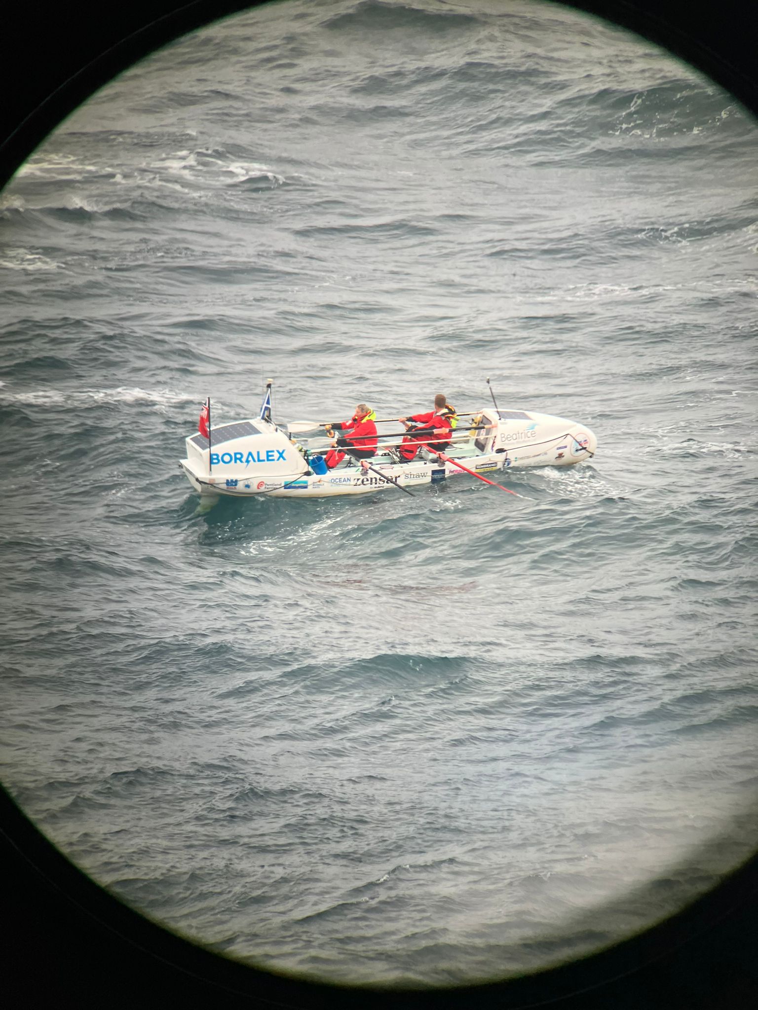 Mhairi Ross and Allan Lipp seen in their boat at sea, from a distance through a porthole