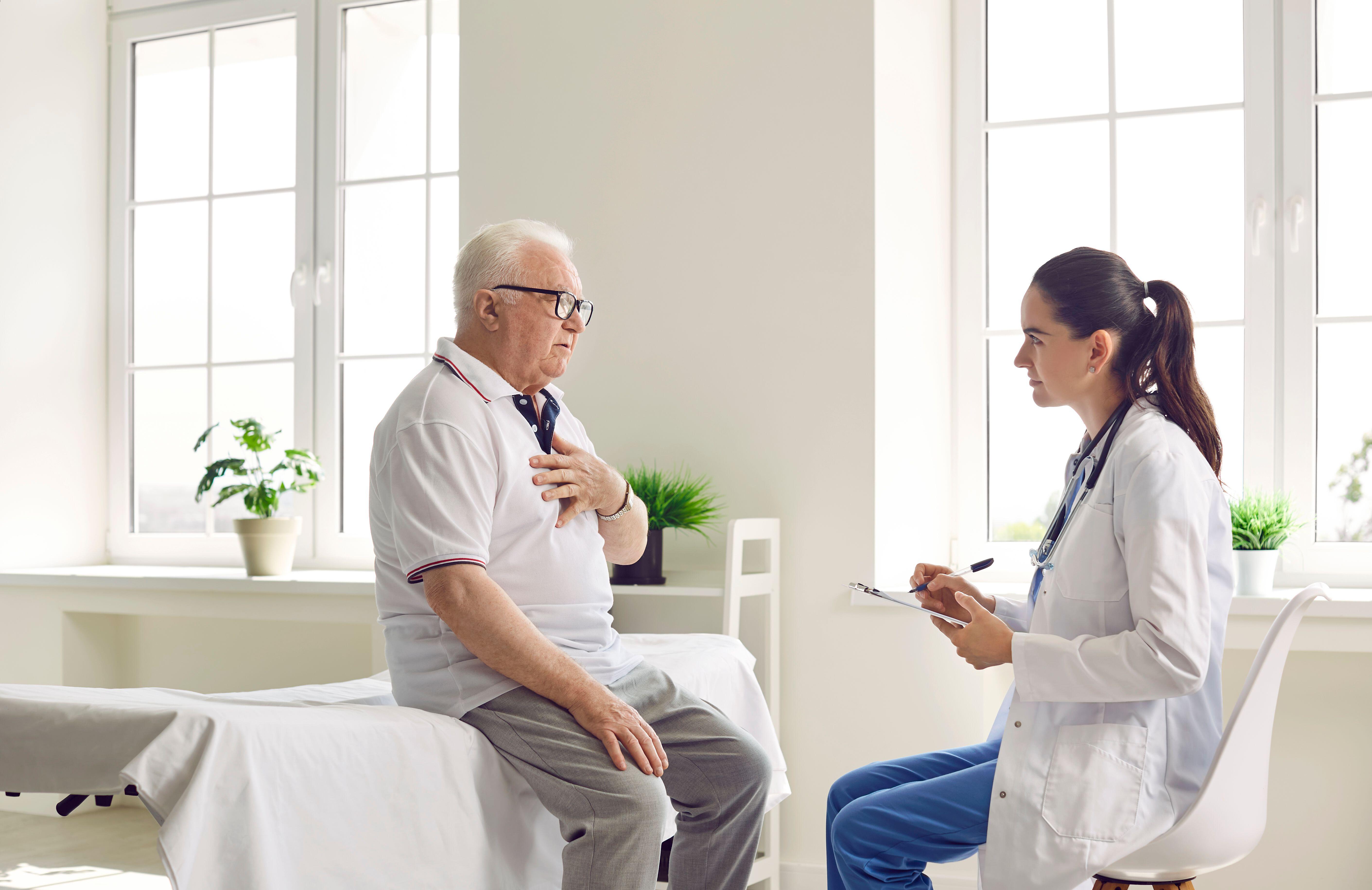 An elderly man with glasses talking to a doctor in a white coat