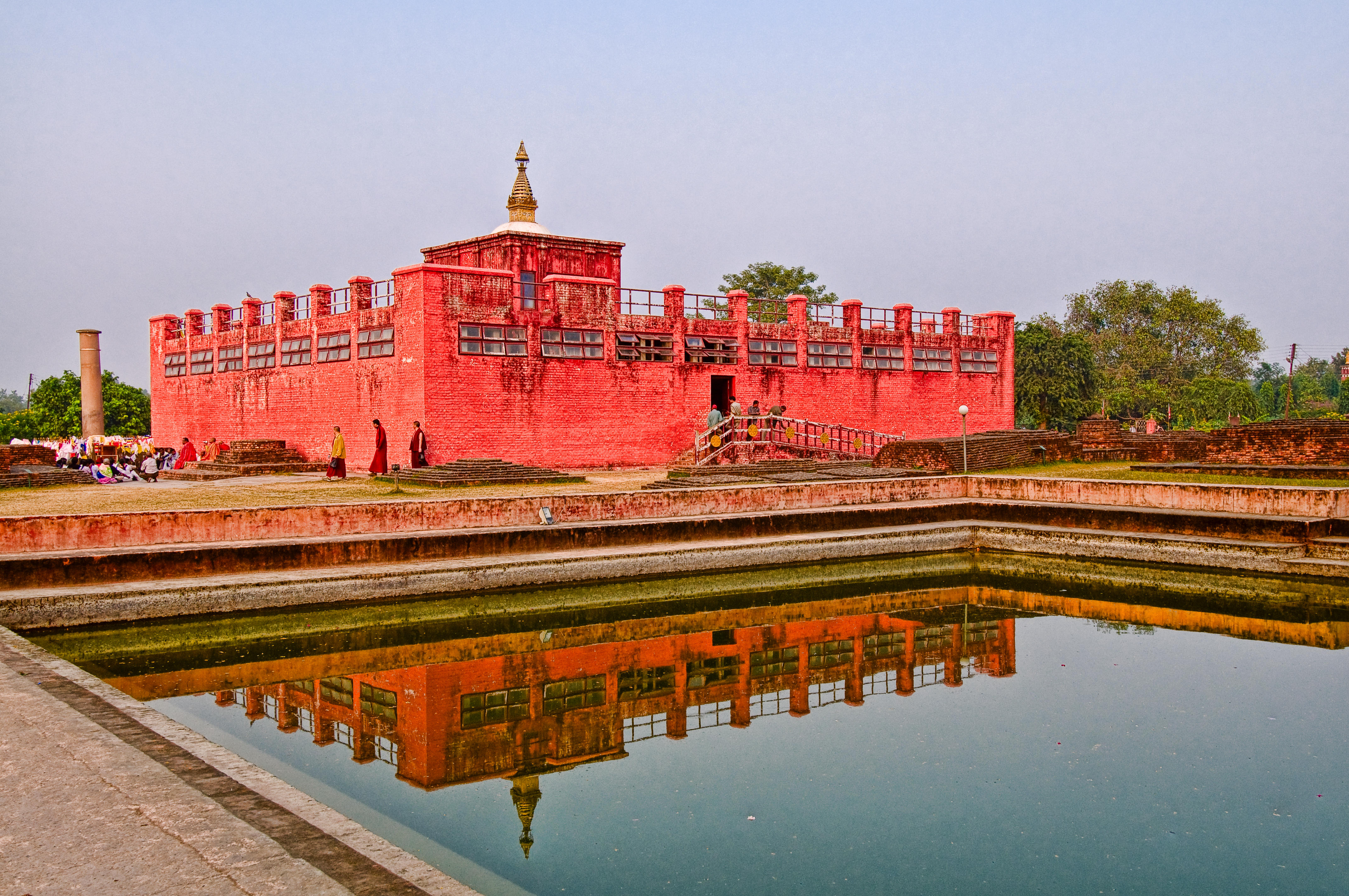 A red temple stands behind a pool of water