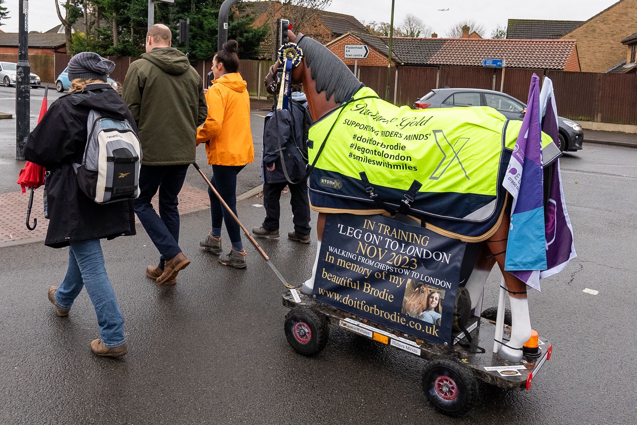 Emma Webb and the Prince of Wales with others seen from behind pulling a resin horse on wheels