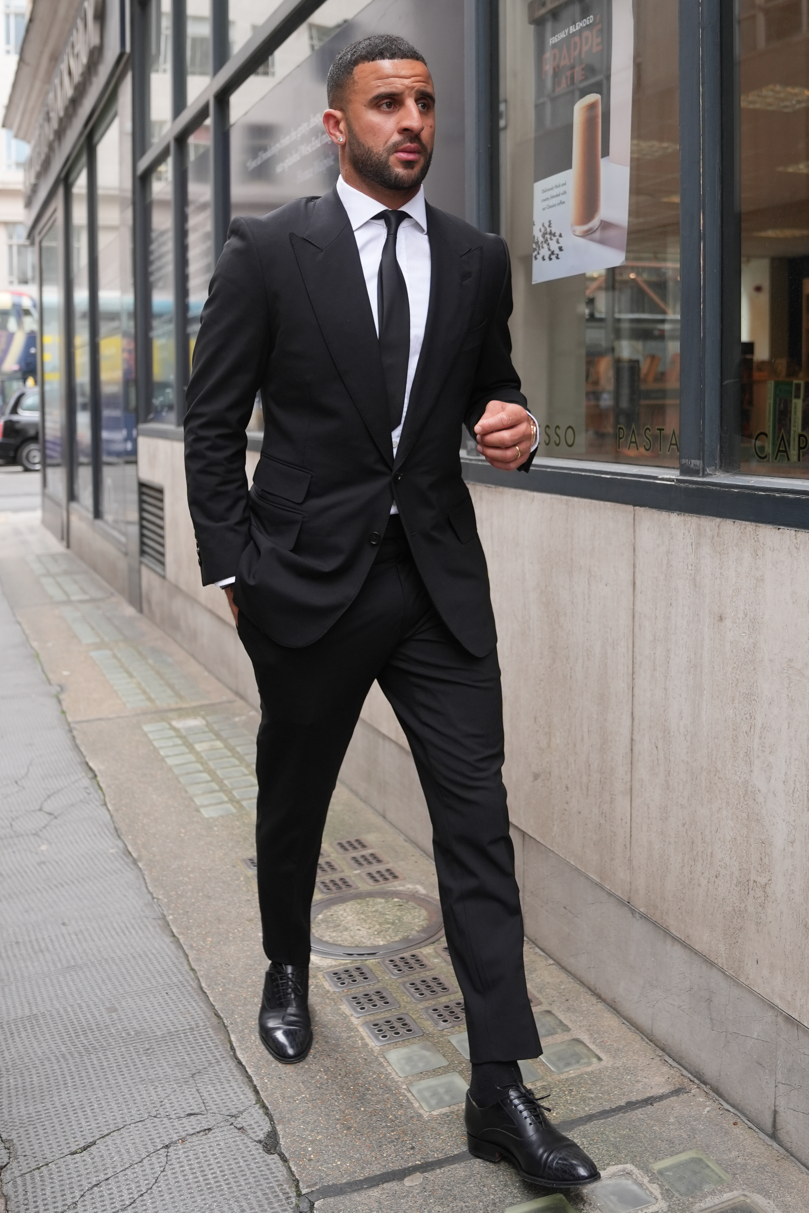 Kyle Walker in black suit walking along a street