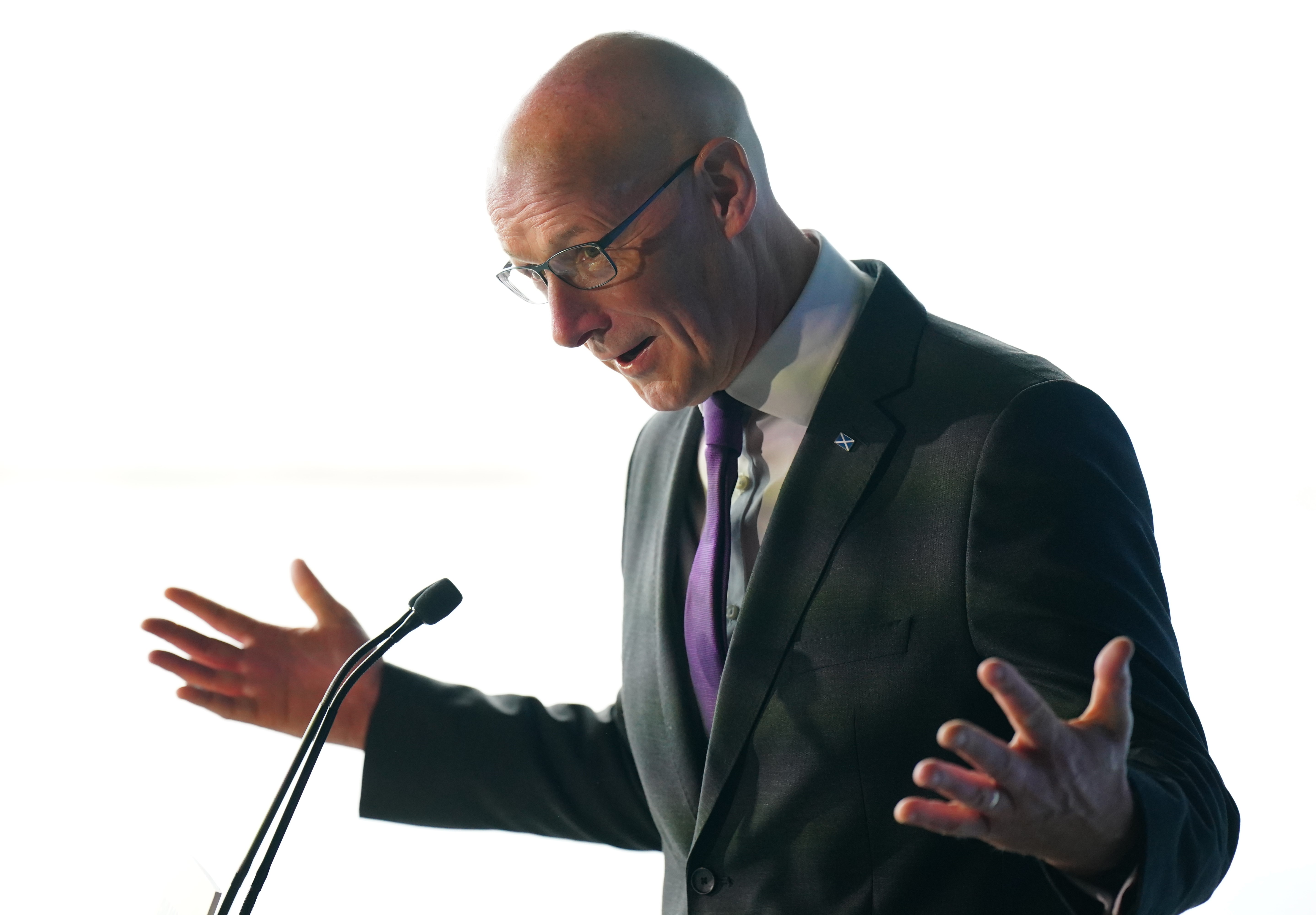 First Minister John Swinney speaking into a microphone