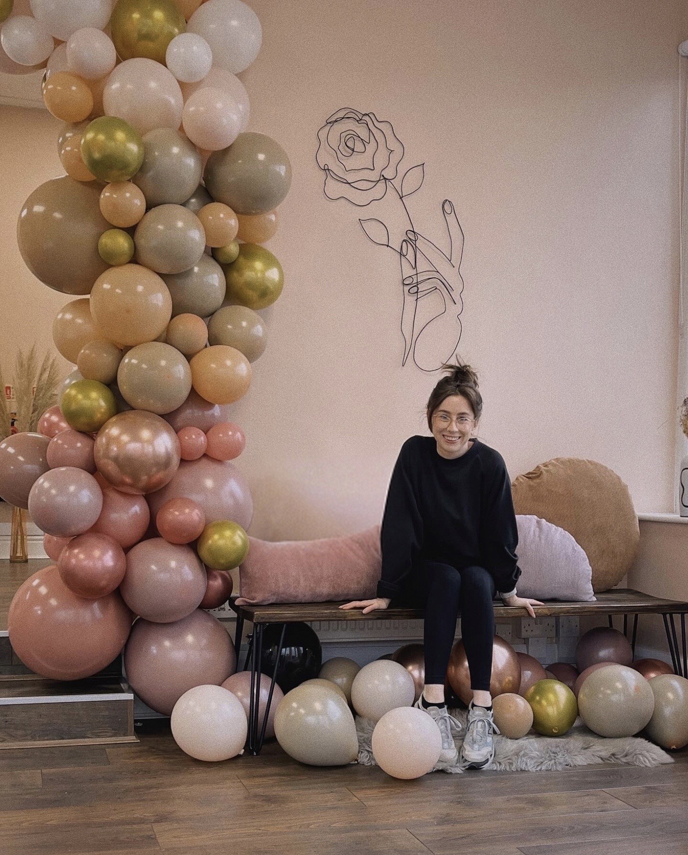 Woman sat on a table surrounded by balloons