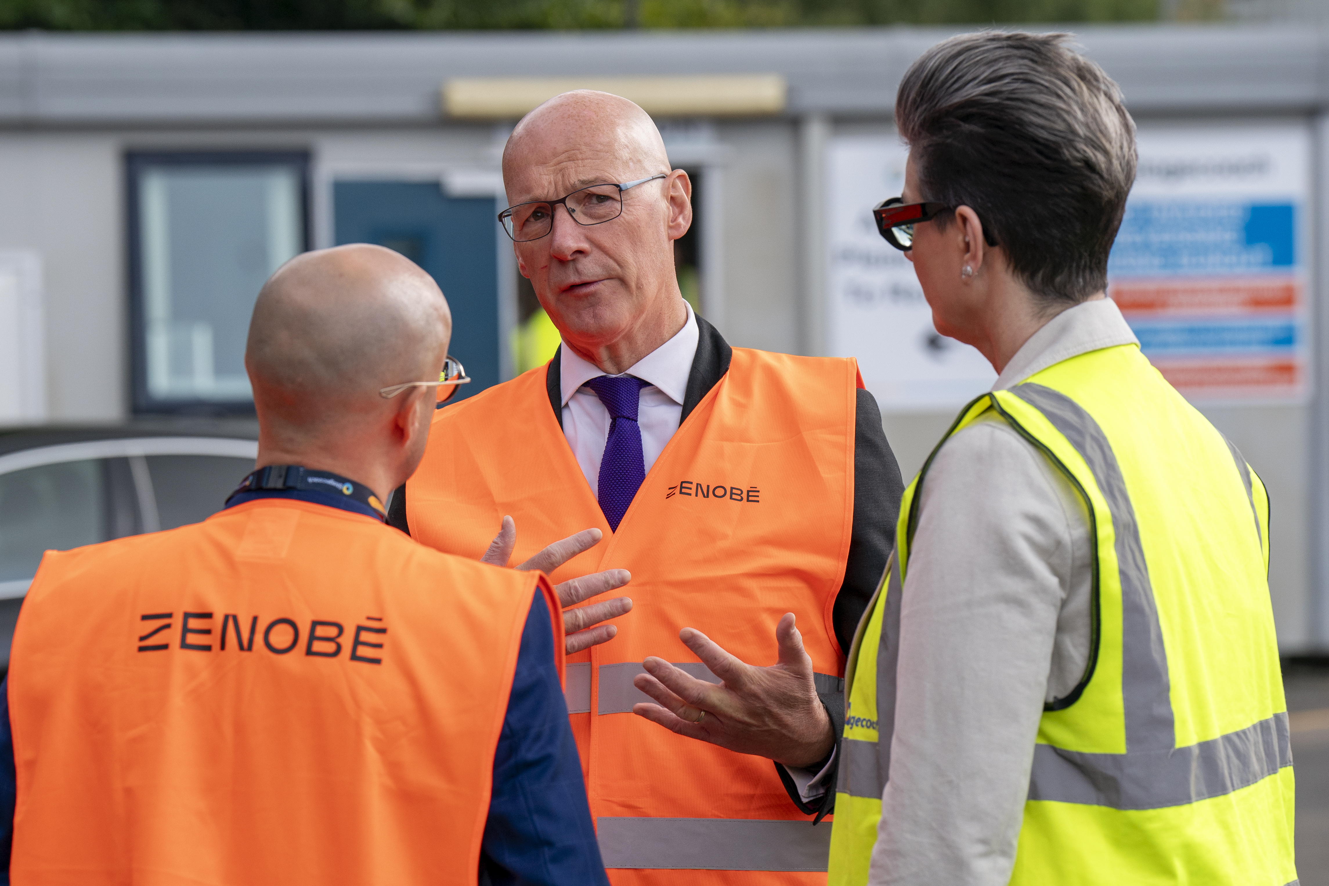 John Swinney wearing hi-vis vest while speaking to two people