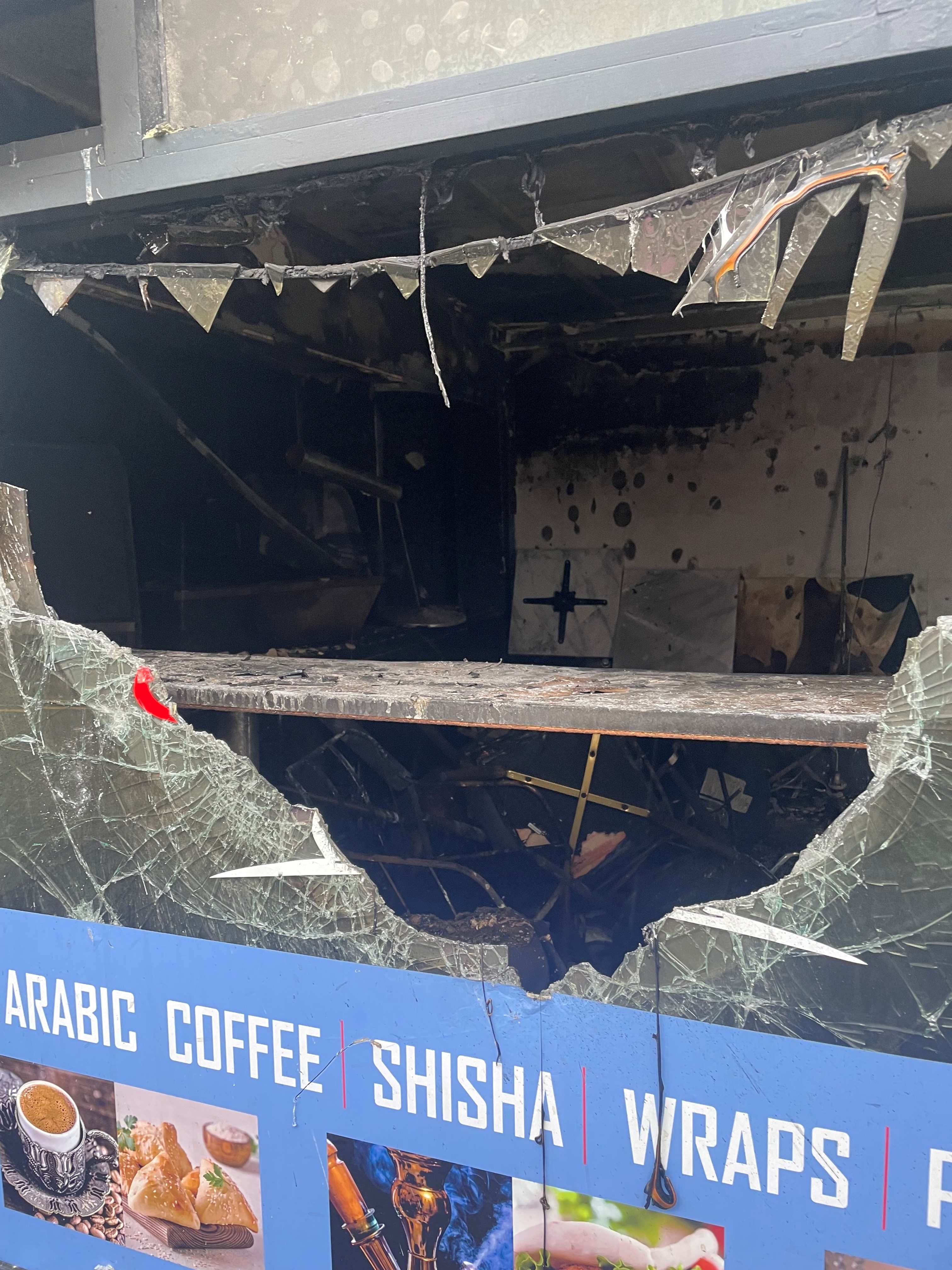 A view through a broken window of the inside of a burnt-out business premises